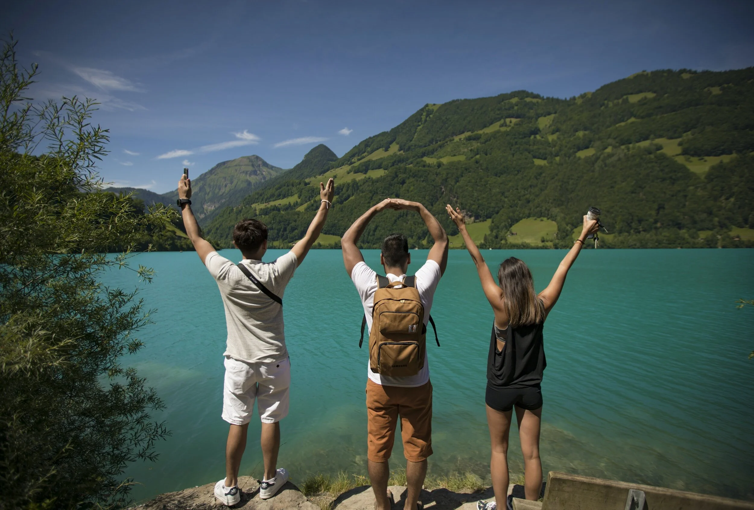 Three hikers overlooking a lake and mountains