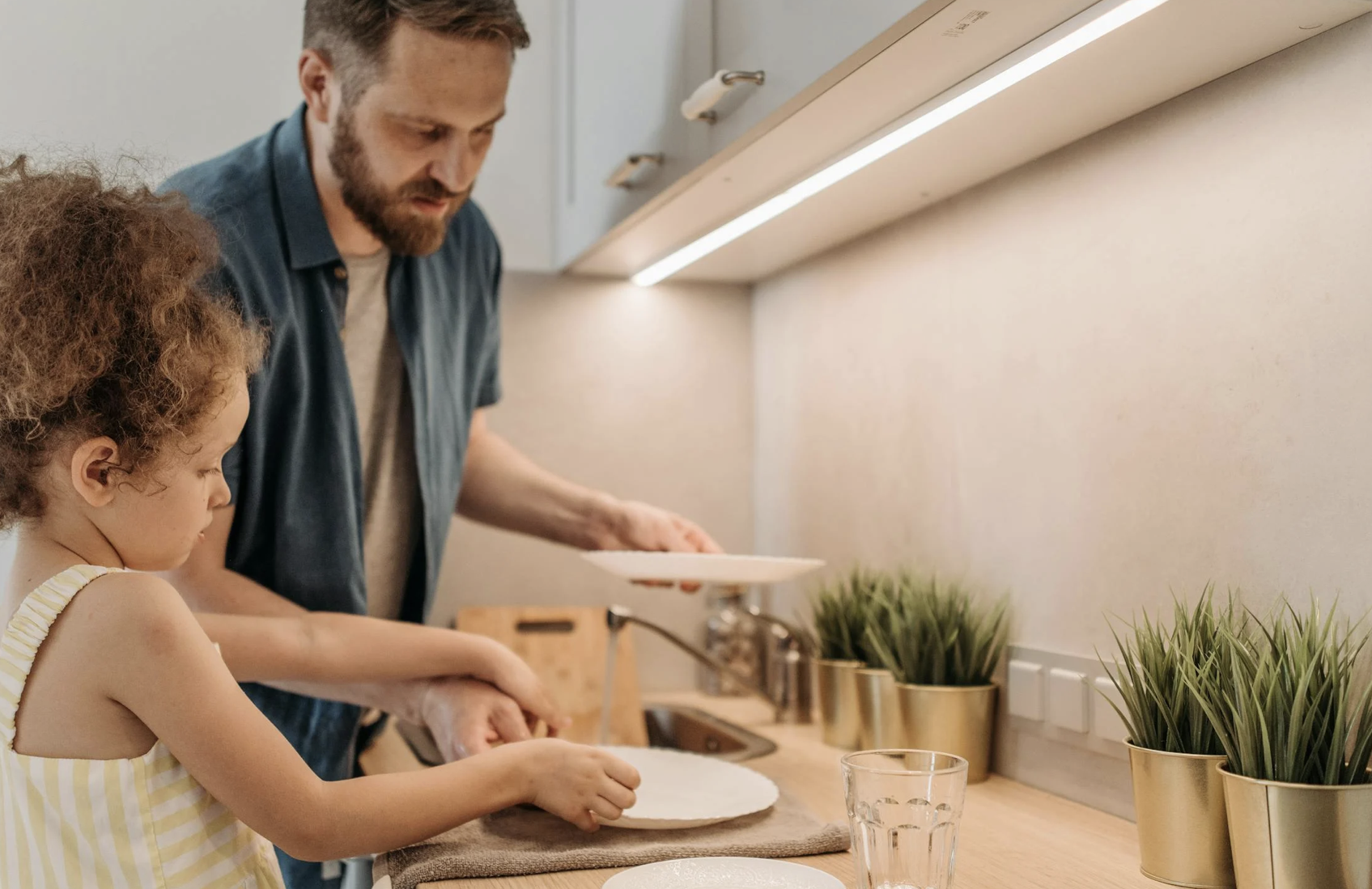 A man and little girl doing disehs in the kitchen
