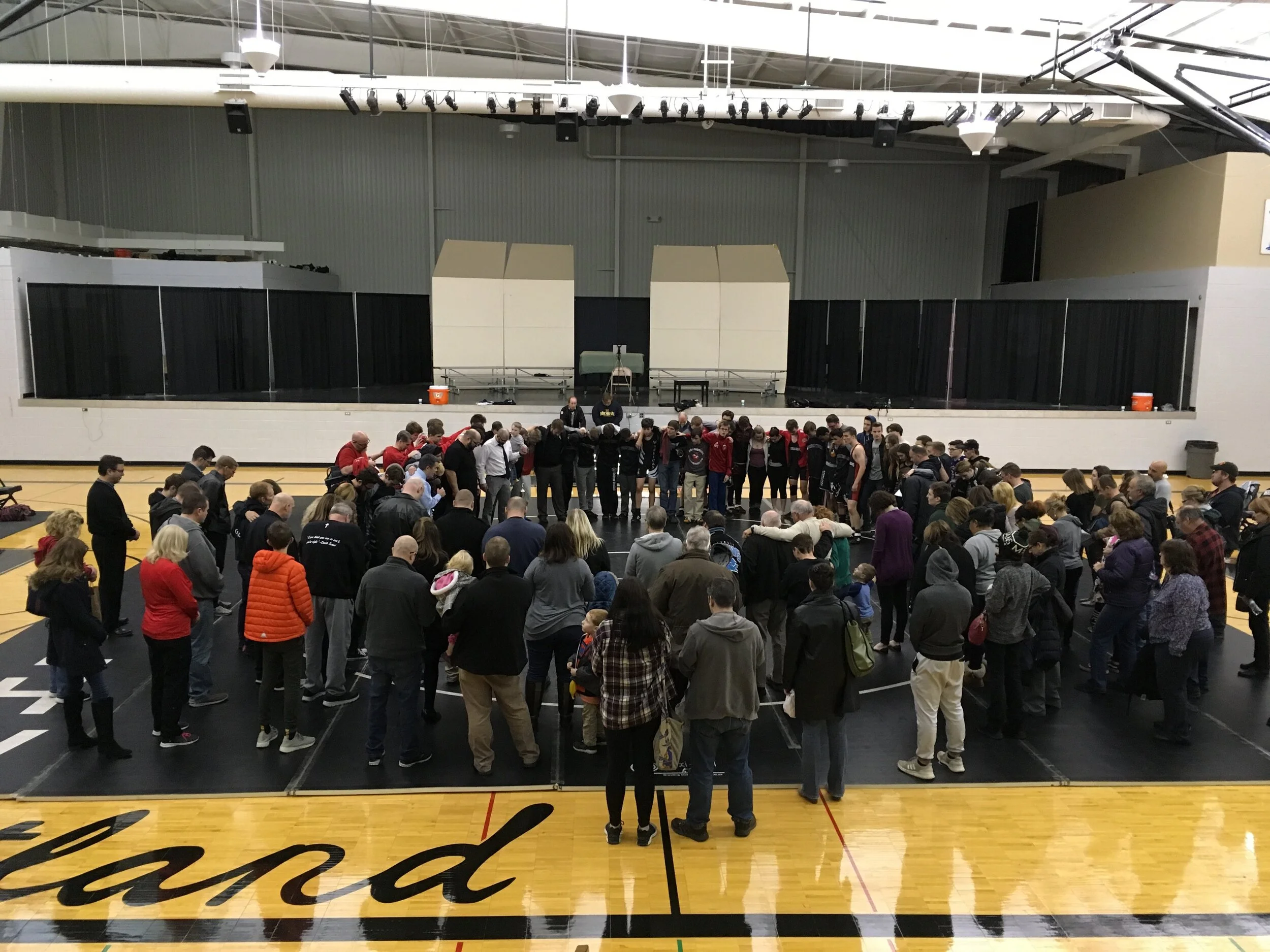Coach Tuomi invited all fans, players, and coaches to the mat to pray after the LHN, LHNW, and LHWL wrestling mat. The prayer was lead by Rev. Dr. Evan Gaertner who wrestled for Lutheran North and whose son now wrestles for Lutheran Northwest.