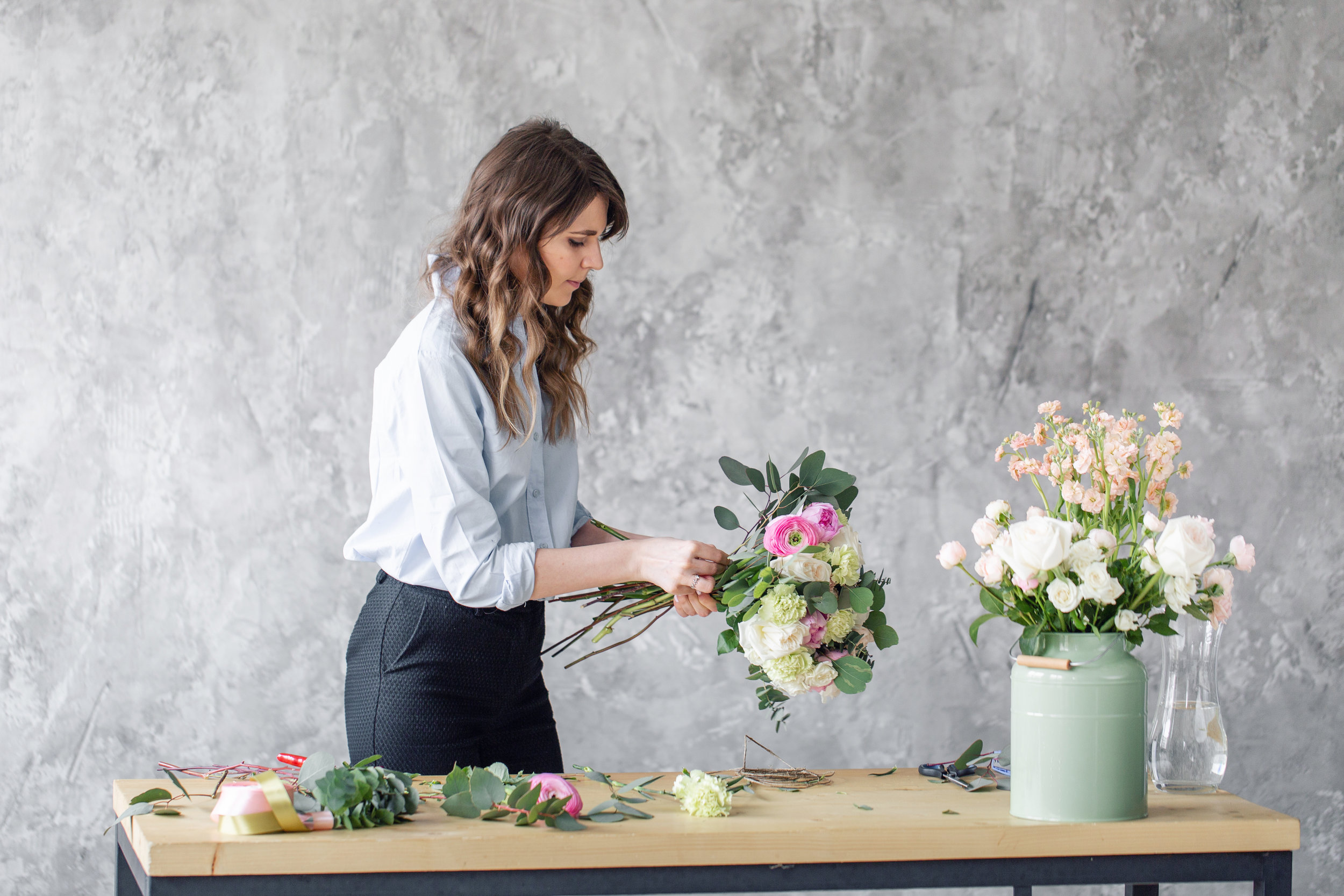 Woman florist creating beautiful bouquet in flower shop. Working in flower shop. Girl assistant or owner in floral design studio, making decorations and arrangements.