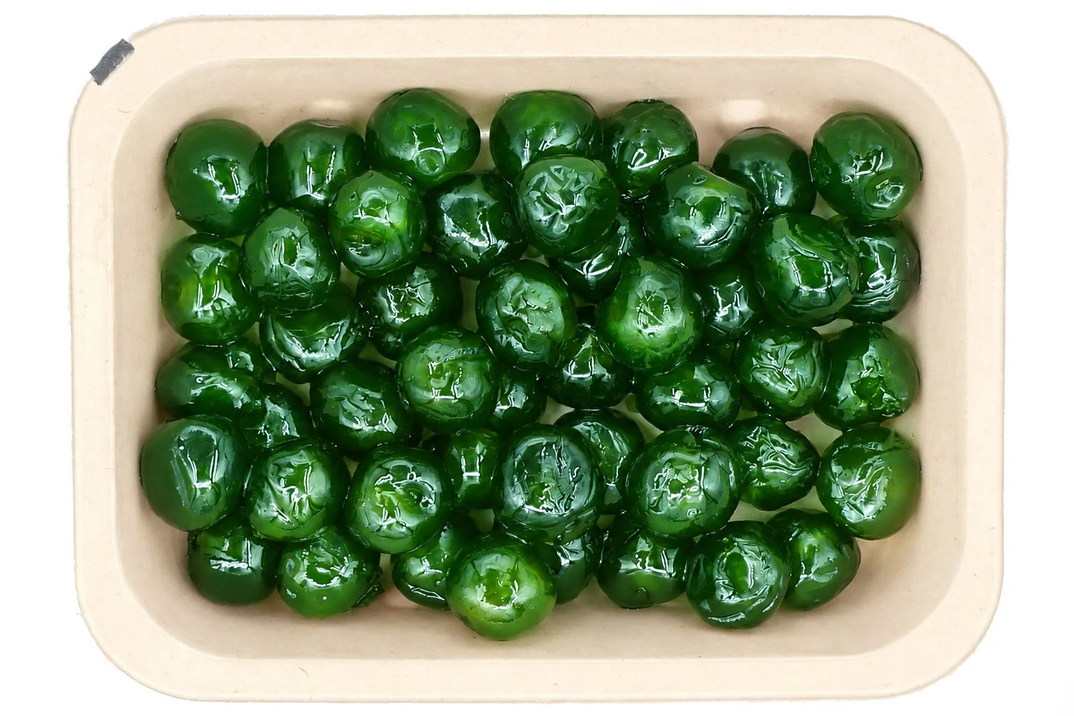 Tray of glossy green glacé cherries photographed from above on a clean white background.