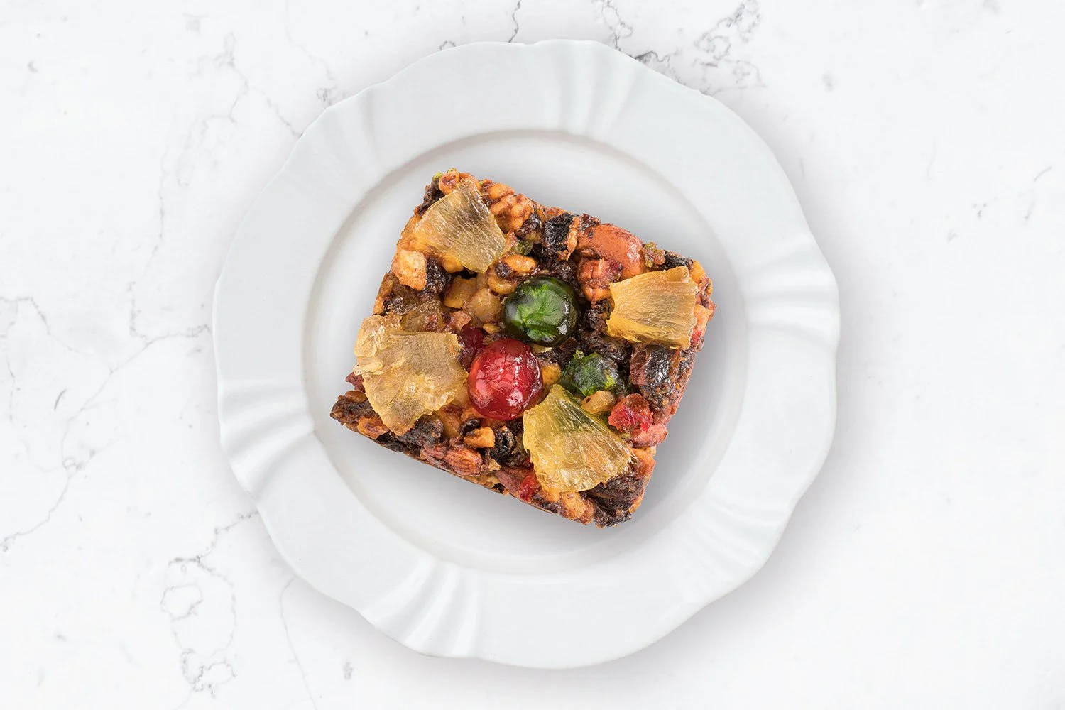 Ditters gourmet cake on white scalloped edged plate on white marble surface