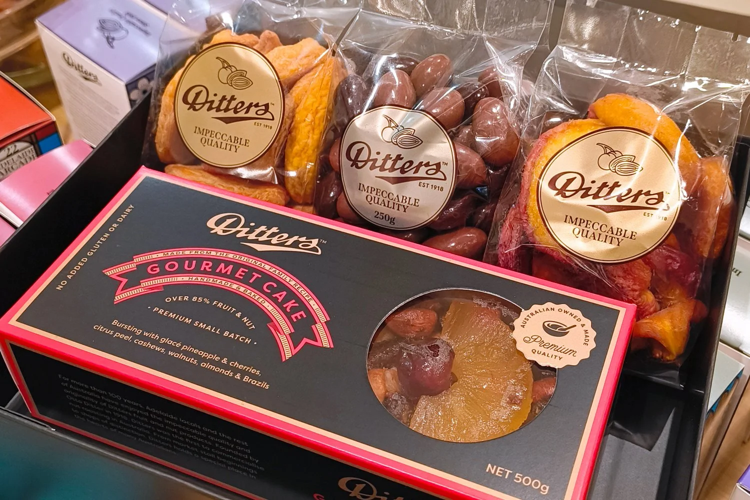 Best of South Australia Gift Hamper with Ditters Gourmet Cake, South Australian Riverland dried peaches and nectarines, and Milk & Dark Scorched Almonds in a black gift box with ribbon.