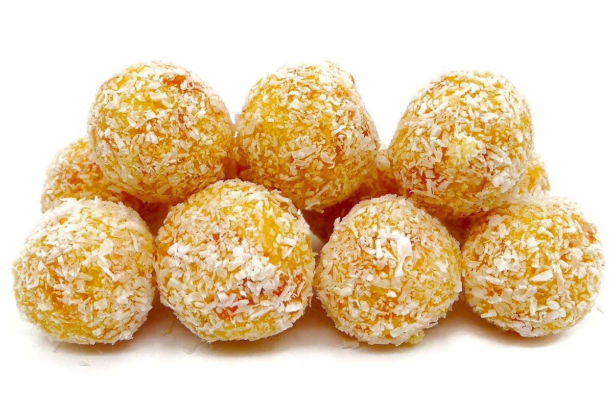 Australian apricot cubes coated in desiccated coconut, isolated on a white background. Bite-sized fruit confection made with dried apricots and coconut.