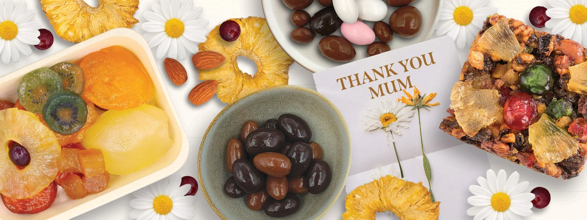 Assortment of glazed fruit, dried pineapple, chocolate coated nuts, dry roasted almonds and a fruit cake next to a card saying thank you mum