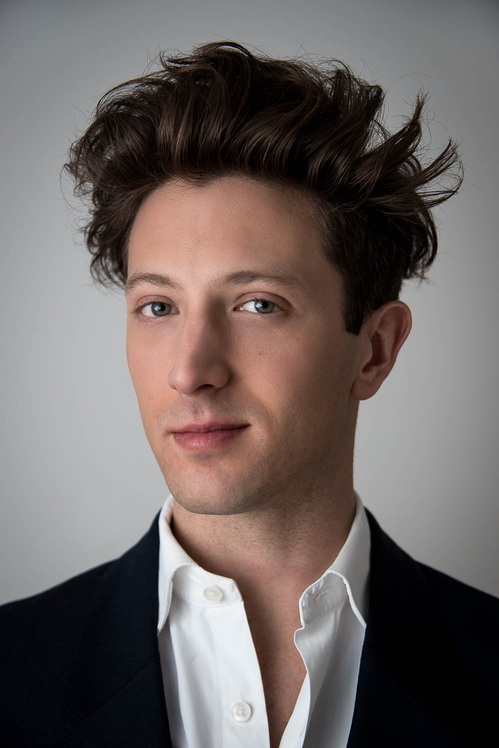  Moody headshot of man in business attire, with half his face in shadow. 