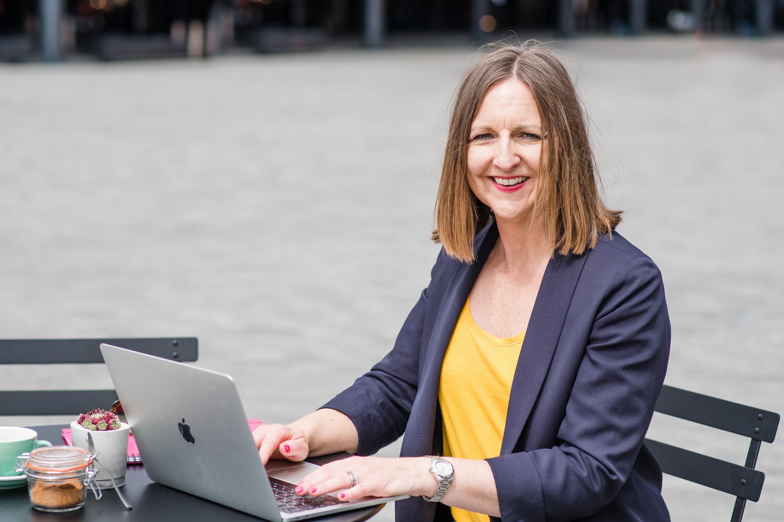  Business woman works on her laptop at an outdoor cafe for personal branding shoot 