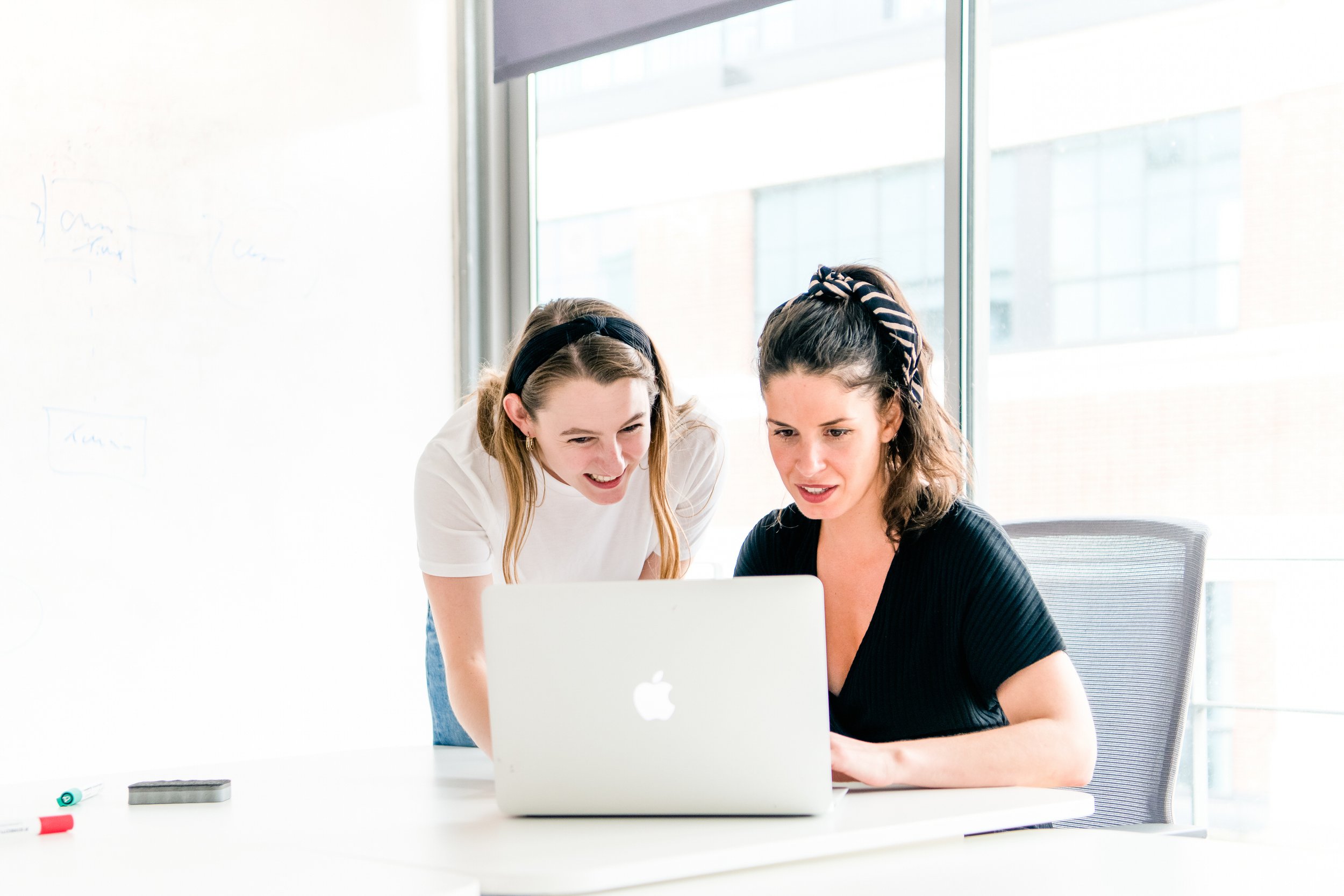  Well lit image of 2 business women looking at a laptop. 