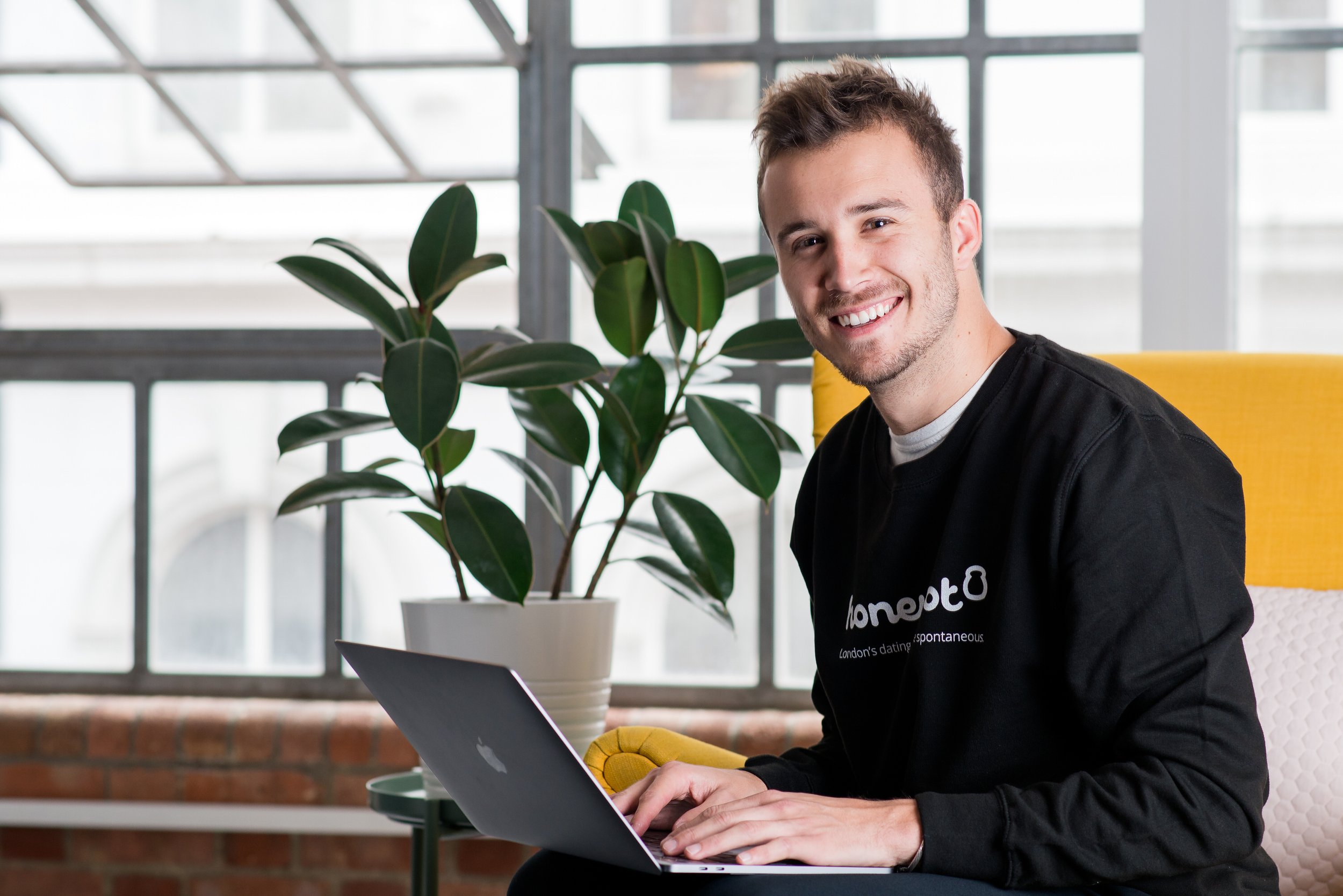  Young business man smiling  with a laptop on his lap. 