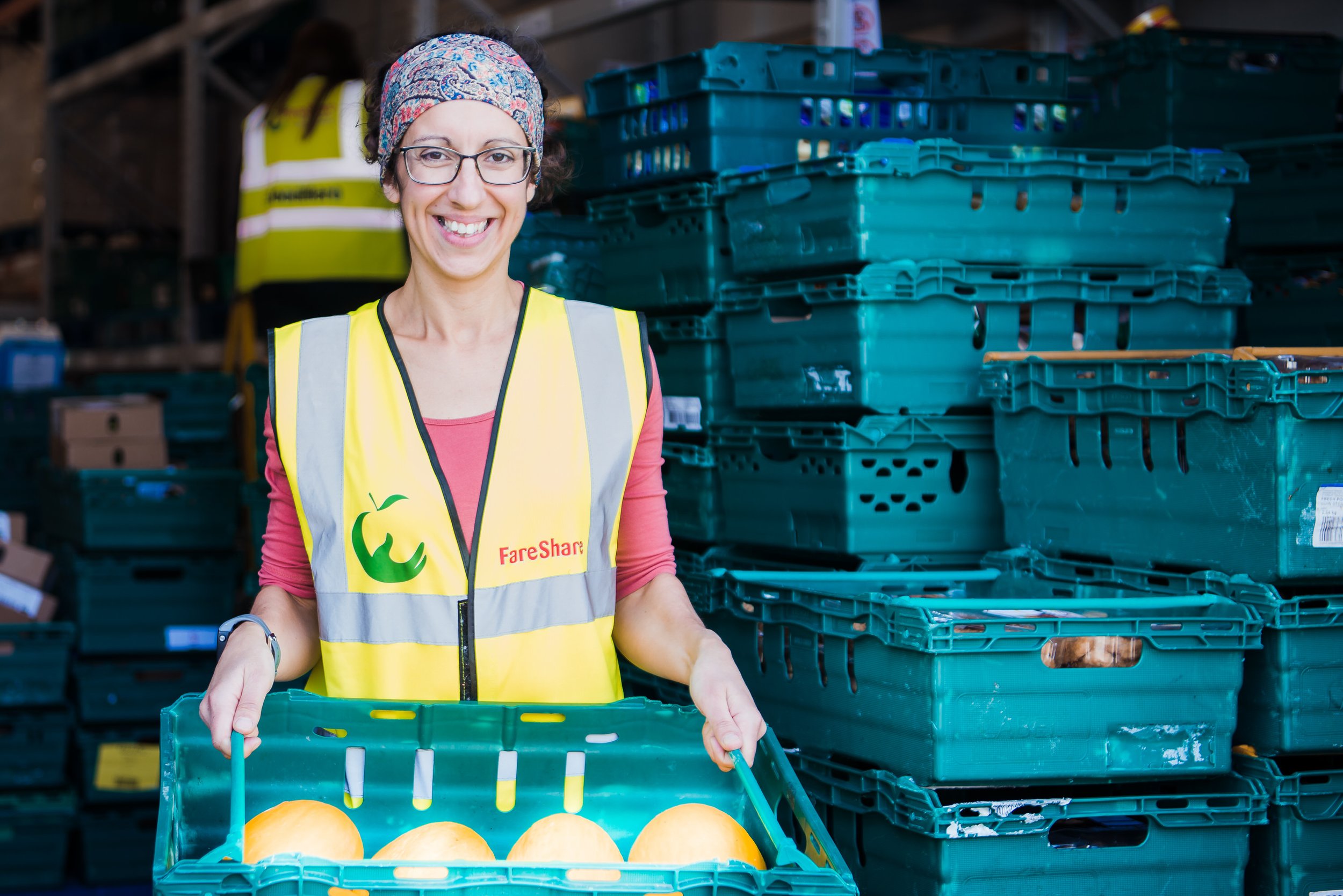  Lady in high vis jacket, holding a tray of food at a warehouse. 