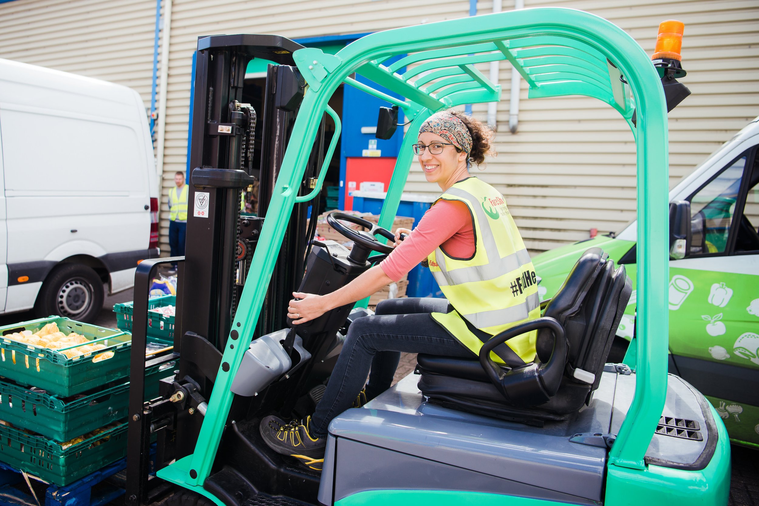  Woman driving a fork lift truck in high vis jacket. 