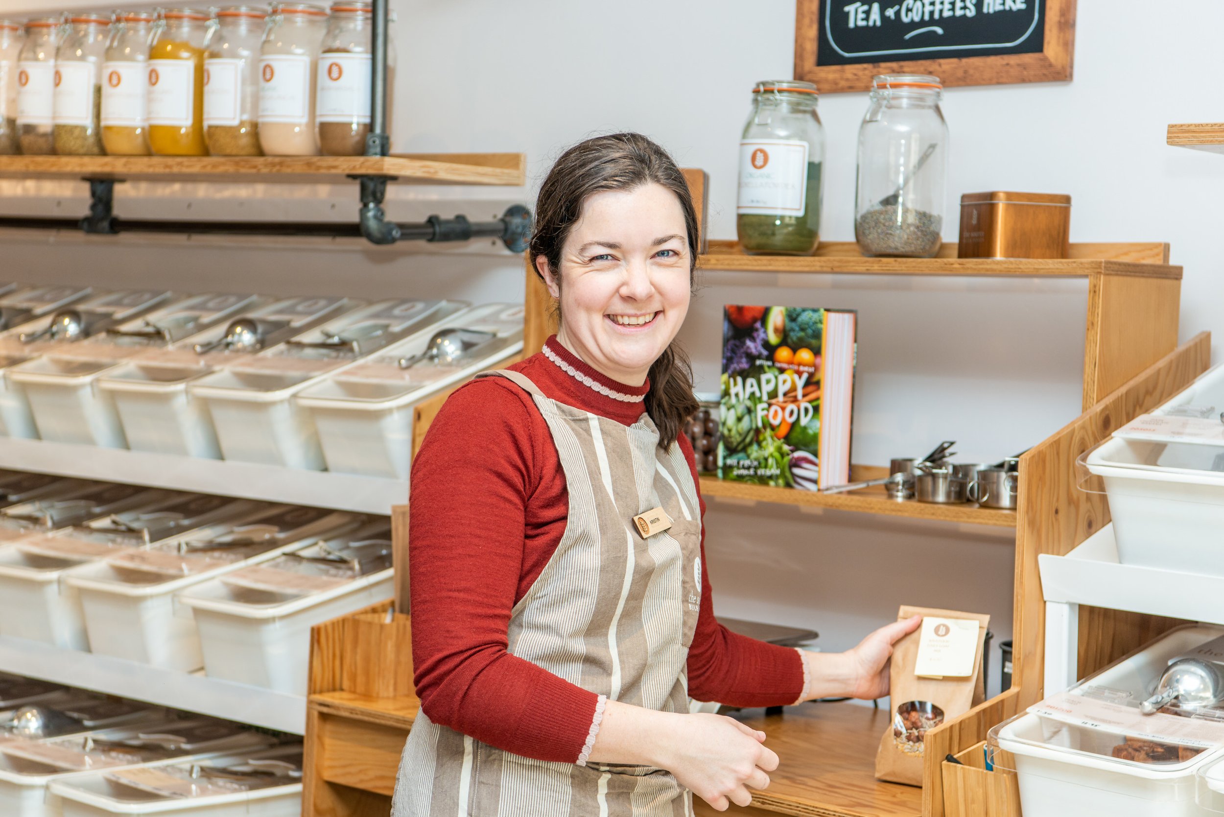  Food shop worker smile while she restocks shelves. 