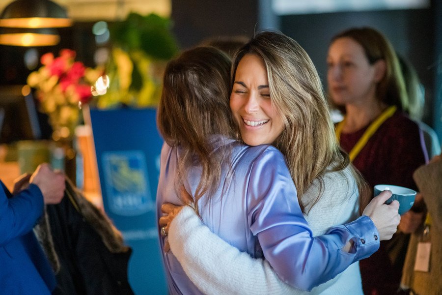 Two women hugging at work event