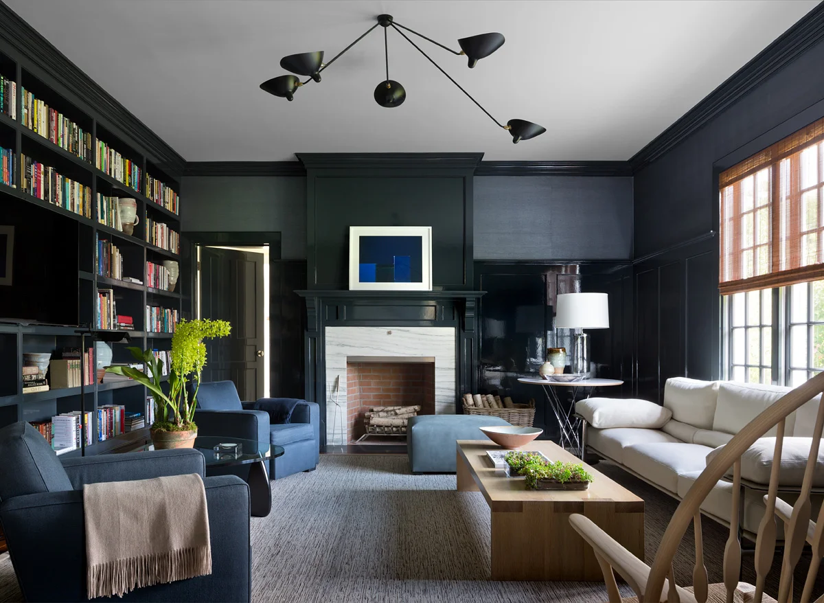 A dark and cozy library with grasscloth wallpaper and Serge Mouille lighting. Photography by Andrew Frasz.