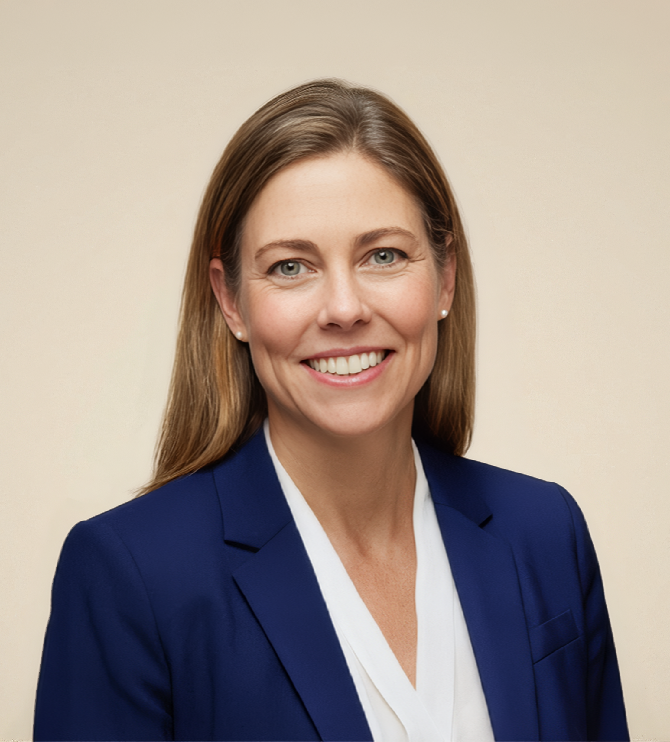 Professional woman with long brown hair, wearing a blue blazer and white blouse, smiling against a light neutral background.