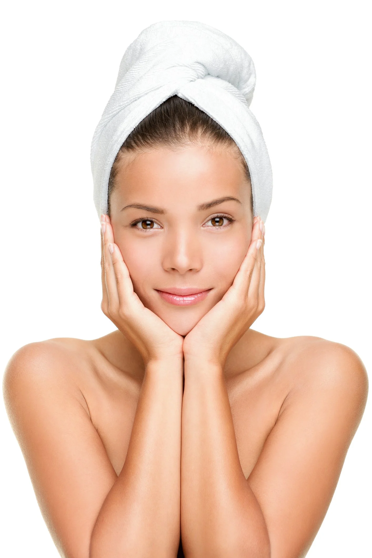 A woman with a towel wrapped around her hair, touching her face gently with her hands, smiling softly, with clear skin and a bare shoulder, against a white background.