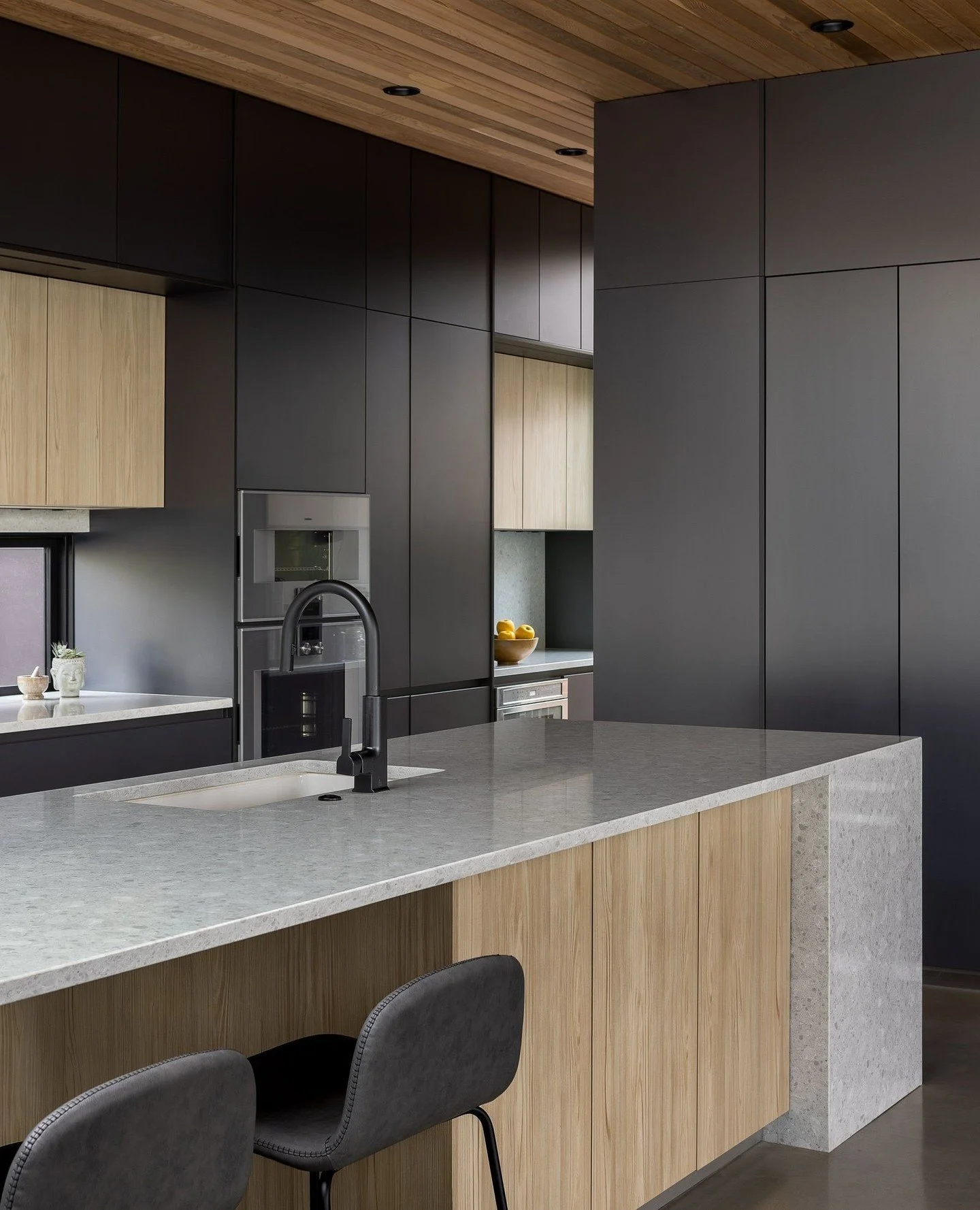 Floor-to-ceiling, luxurious flat front cabinetry anchor the kitchen space of this Greenlake residence. Cedar ceiling panels and wood veneer cabinetry add an element of warmth.⁠
⁠
Dark, rich wall cabinetry provides endless storage, including a wine fr