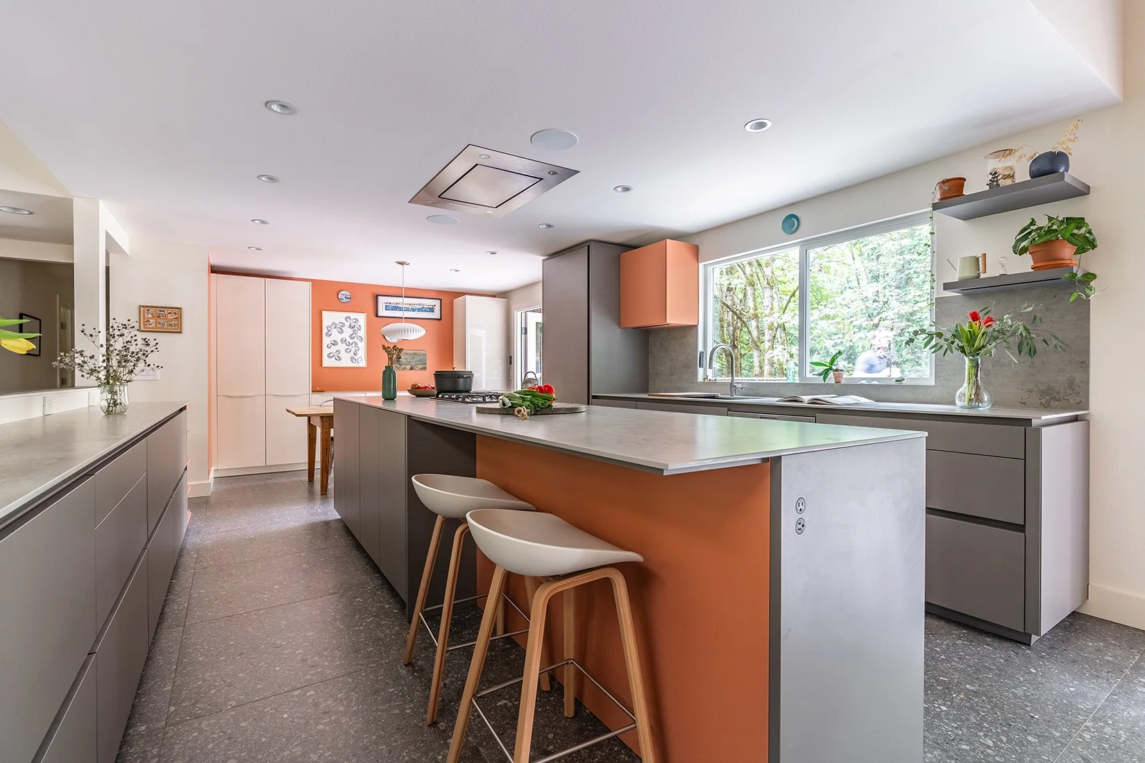 Two toned luxury gray kitchen in Sammamish, Washington using both gray and orange in a minimalist space with prominent kitchen island and seating.