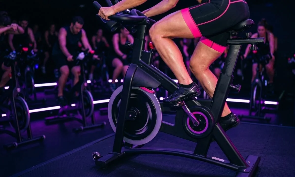 Person doing indoor cycling workout in a spin studio with group class in background