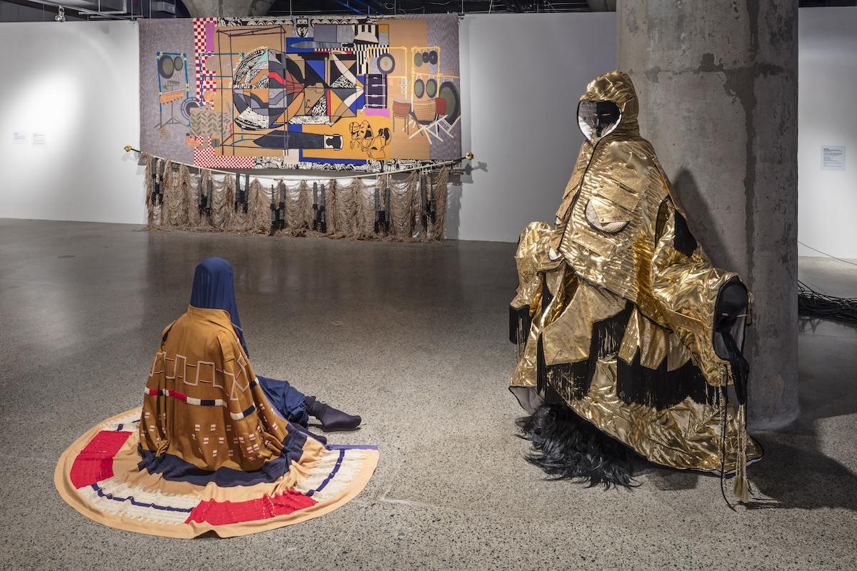 Nep Sidhu's No Pigs in Paradise garments and his tapestry, The Sound Sculpture Forms & Knowledge Transfers of Kahil El’Zabar (When My Drums Come Knocking, They Watch Series). Image by Toni Hafkenscheid