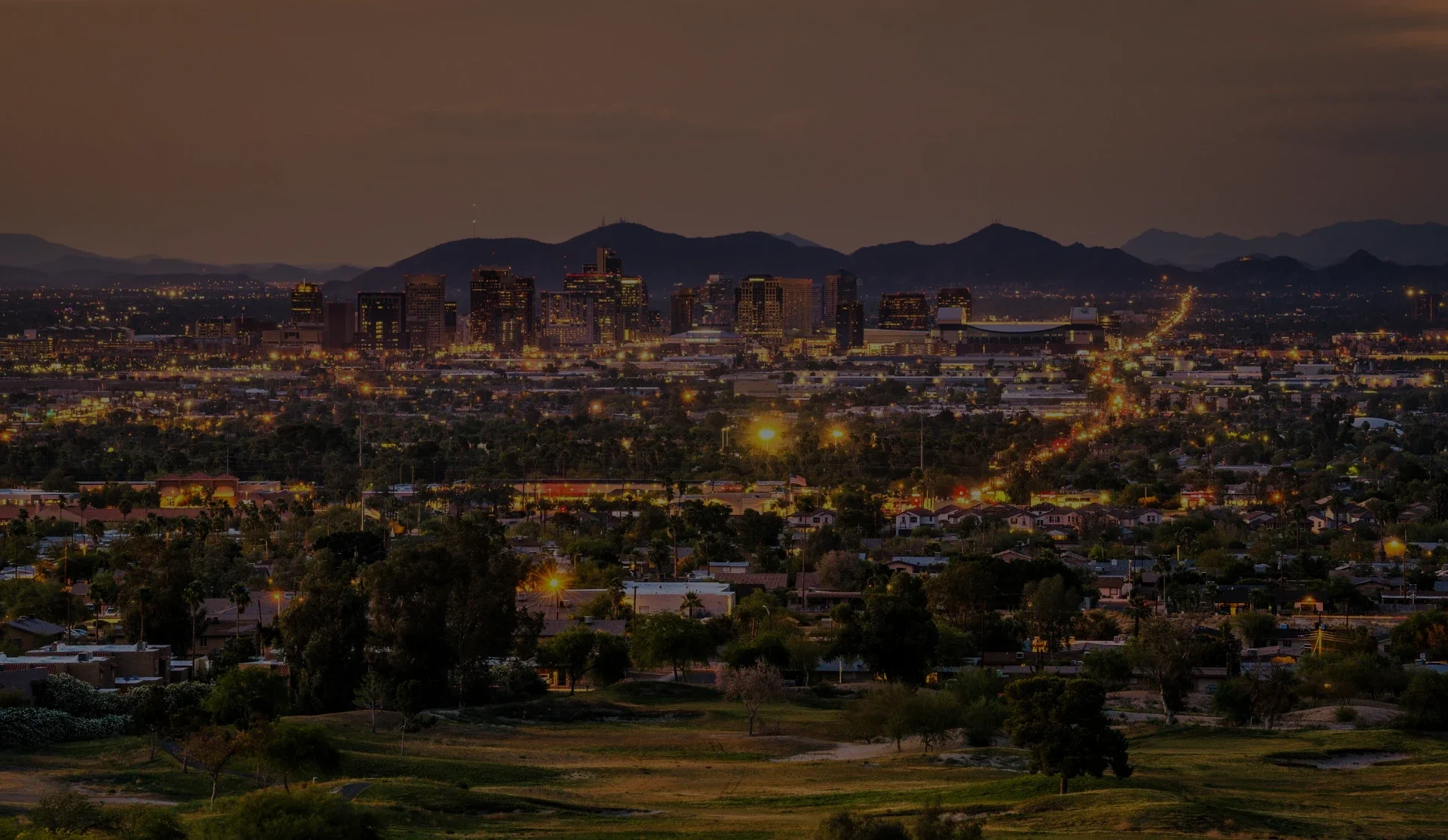 Phoenix skyline at dusk with illuminated downtown buildings and mountains in the background..webp