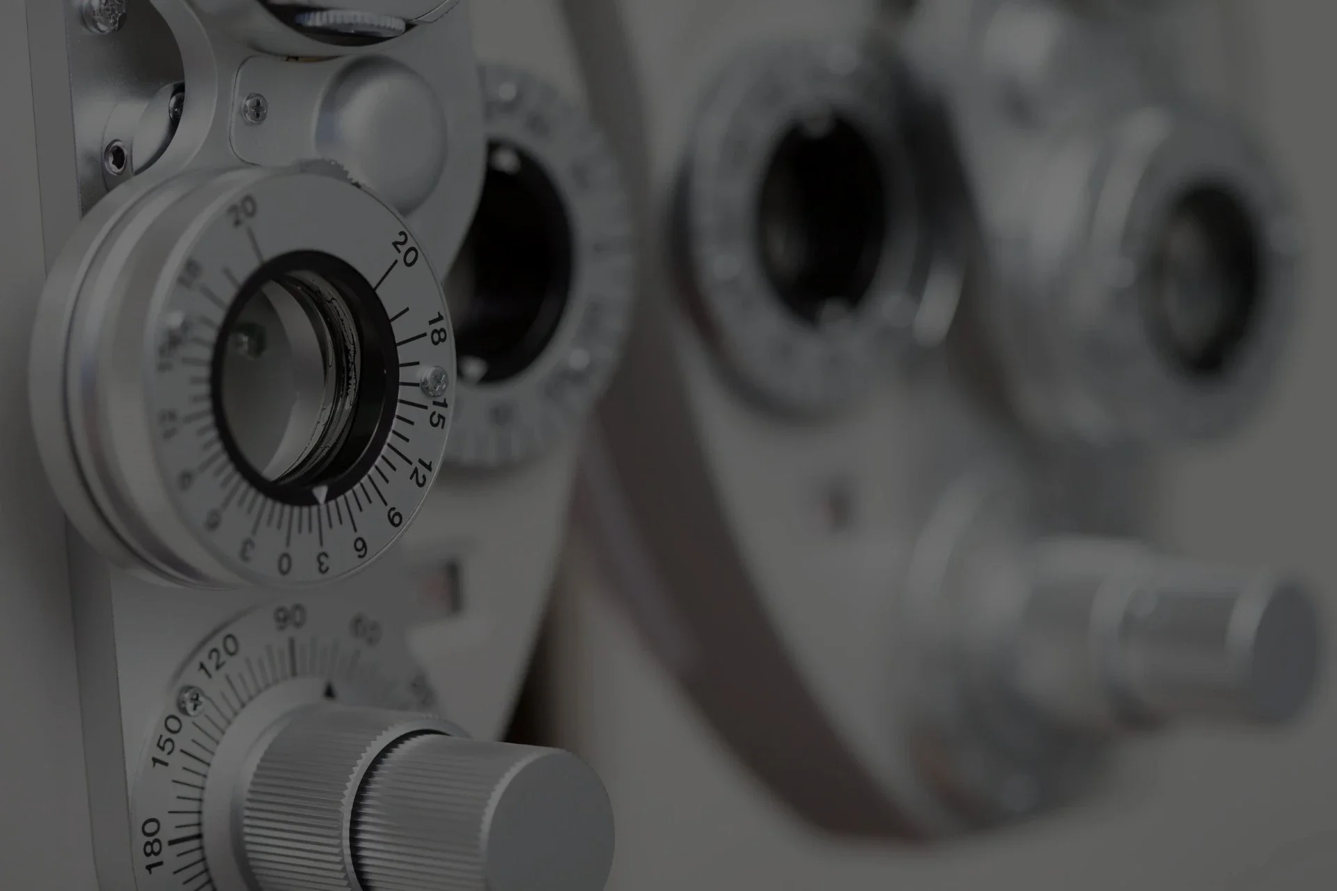 A close-up view of an optometry phoropter with multiple lenses, dials, and numbered adjustment knobs used for eye exams..webp