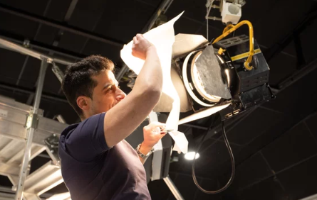 A man operating a large technical or stage lighting fixture.