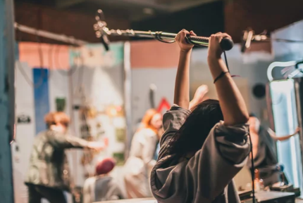 A person holding a boom microphone in a busy recording studio or radio station.