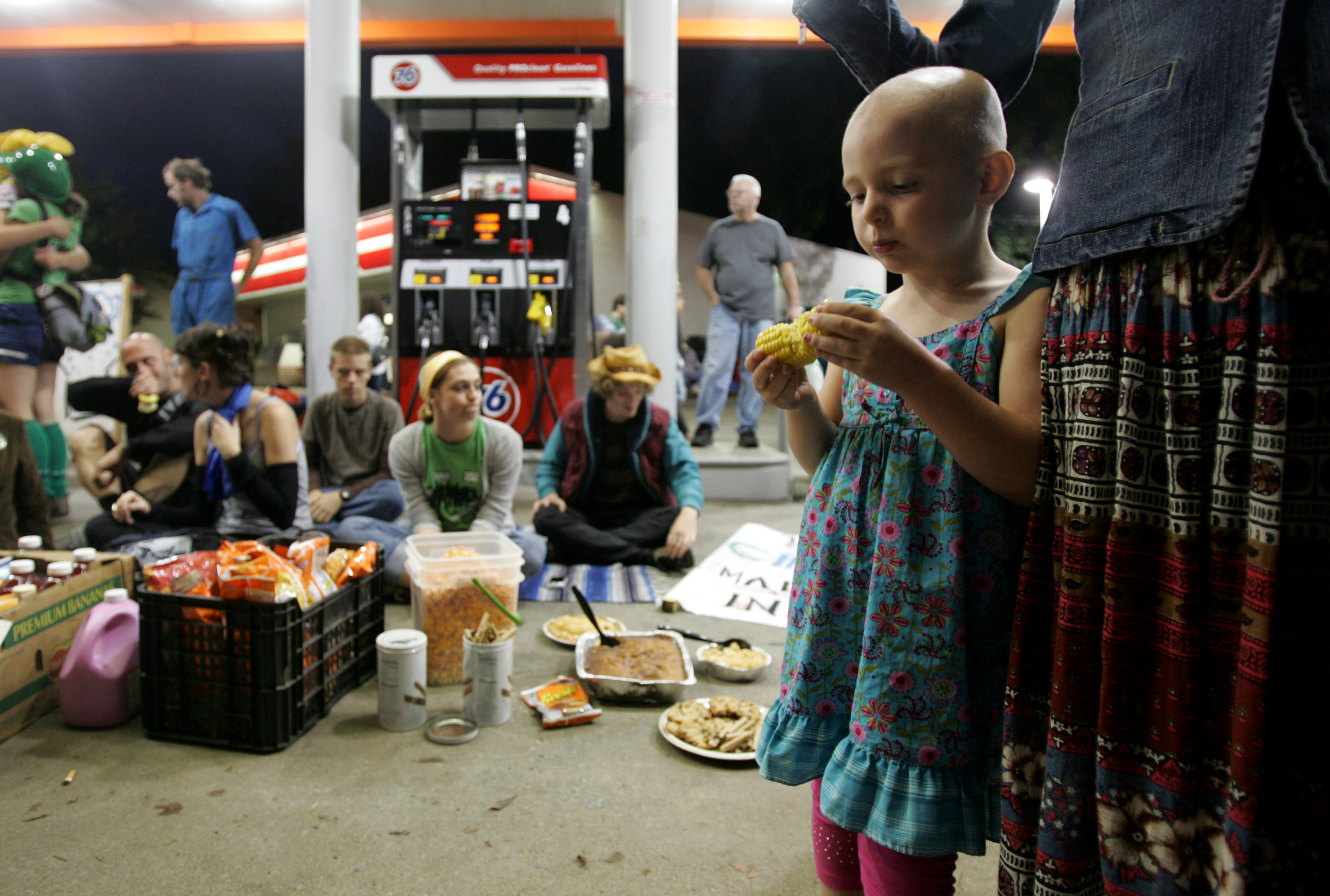  Nova Potter, 4, eats corn on the cob at a gas station where Food not Bombs had set up free food outside the town hall debate.  