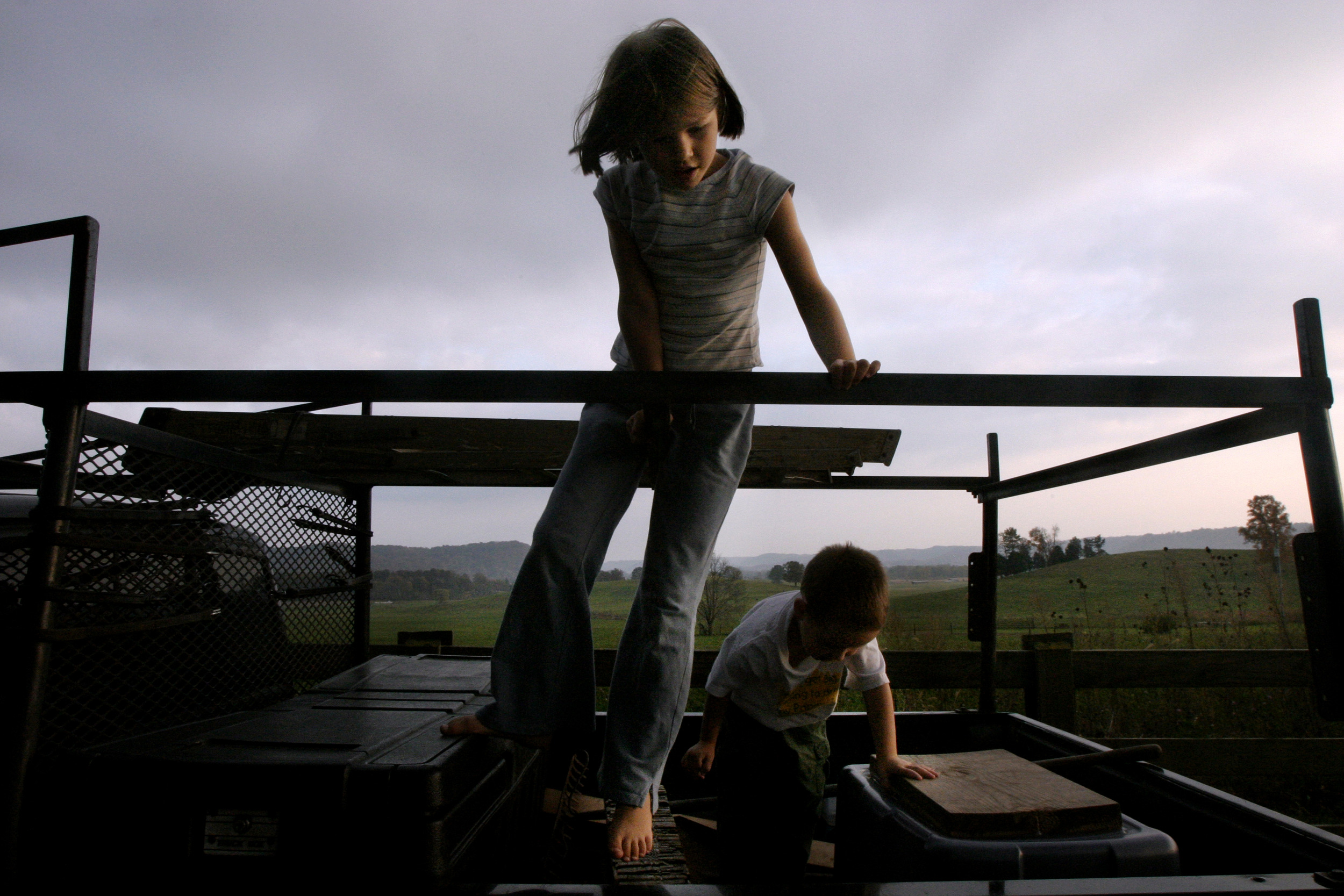  Anna Stewart Burdette, 7, and Tibor, 4 play together on a pickup truck as the sun sets over the vista of rolling hills and fields behind their house. 