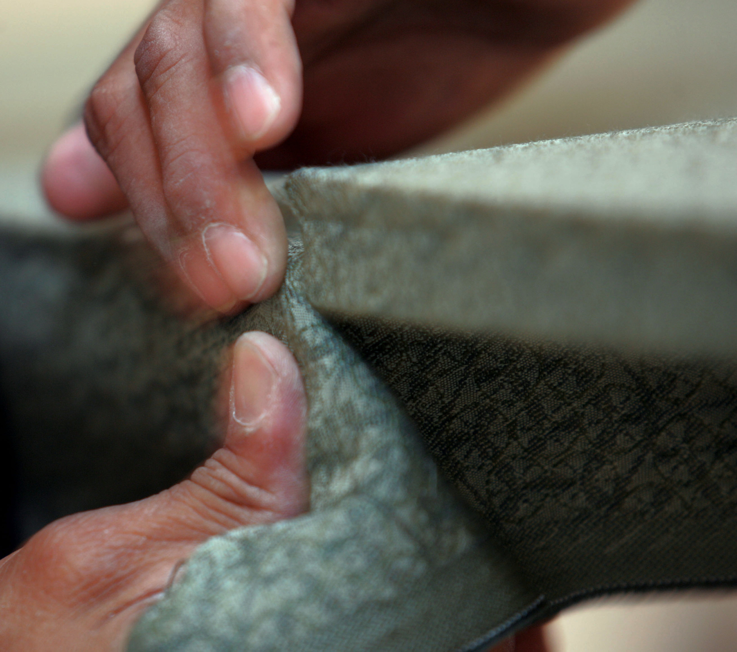  Franscisco Nava of Accutrack Systems carefully folds over the fabric on one of hundreds of acoustical panels that he covered for hallways and rooms.  