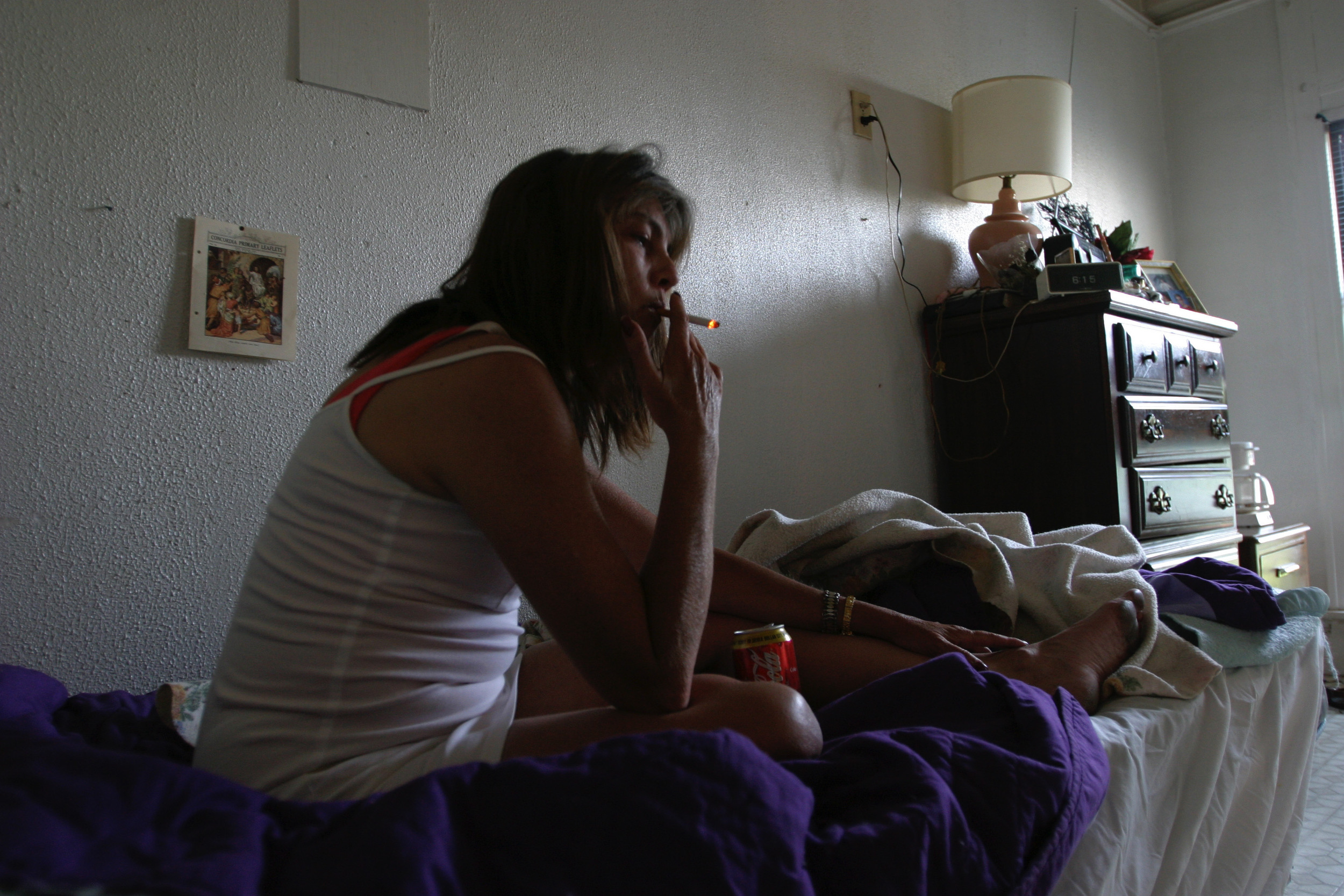 Cynthia has a smoke on her bed at the Drake guesthouse, formerly an upscale hotel in Carthage, Missouri along Route 66, now a group home for mentally and physically disabled. 