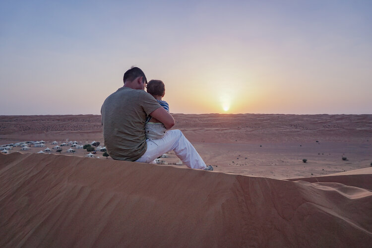 Dad-son-toddler-watching-sunset-from-desert-dunes-overlooking-Desert-Nights-Camp-Oman-Wahiba-Sharqiya-Sands.jpg
