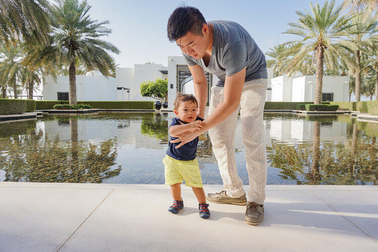 Asian-dad-with-mixed-baby-in-front-water-The-Chedi-Muscat-Oman.jpg