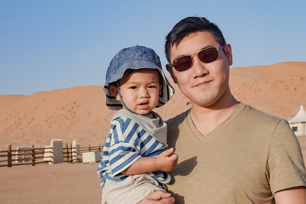 Travel-dad-holding-mixed-toddler-Desert-Nights-Camp-Oman-Wahiba-Sharqiya-Sands.jpg