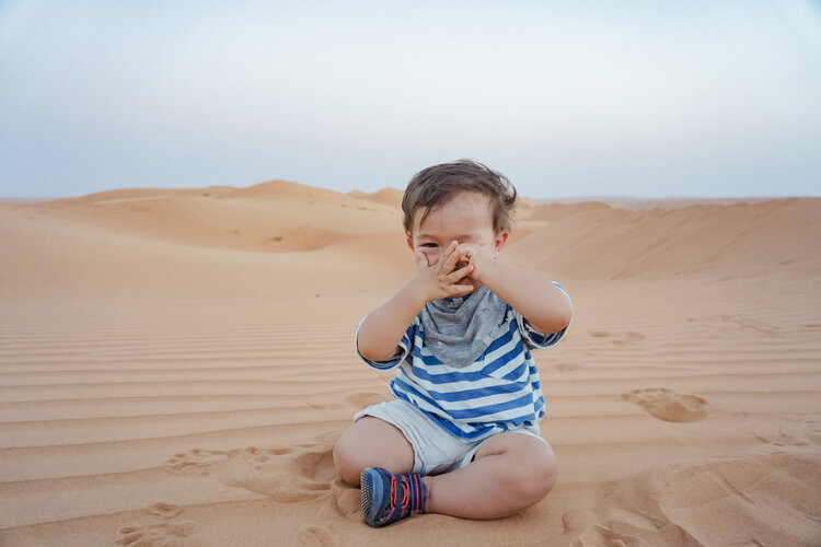 Baby-toddler-covering-eyes-peeking-Oman-Wahiba-Sands-desert-dunes.jpg