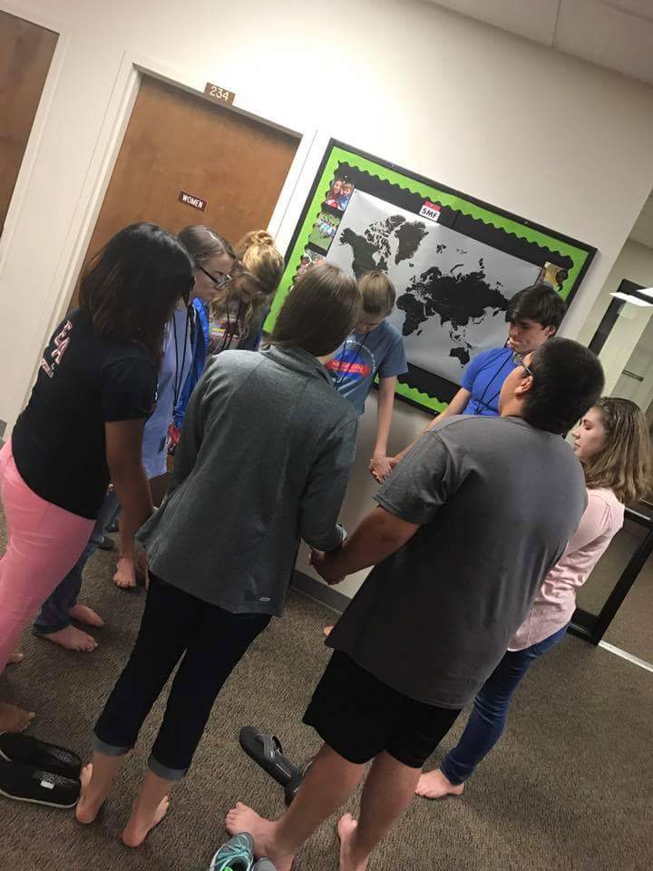   Christian Youth In Action ®  missionaries take time near a map at training to pray over the country of North Korea.    
