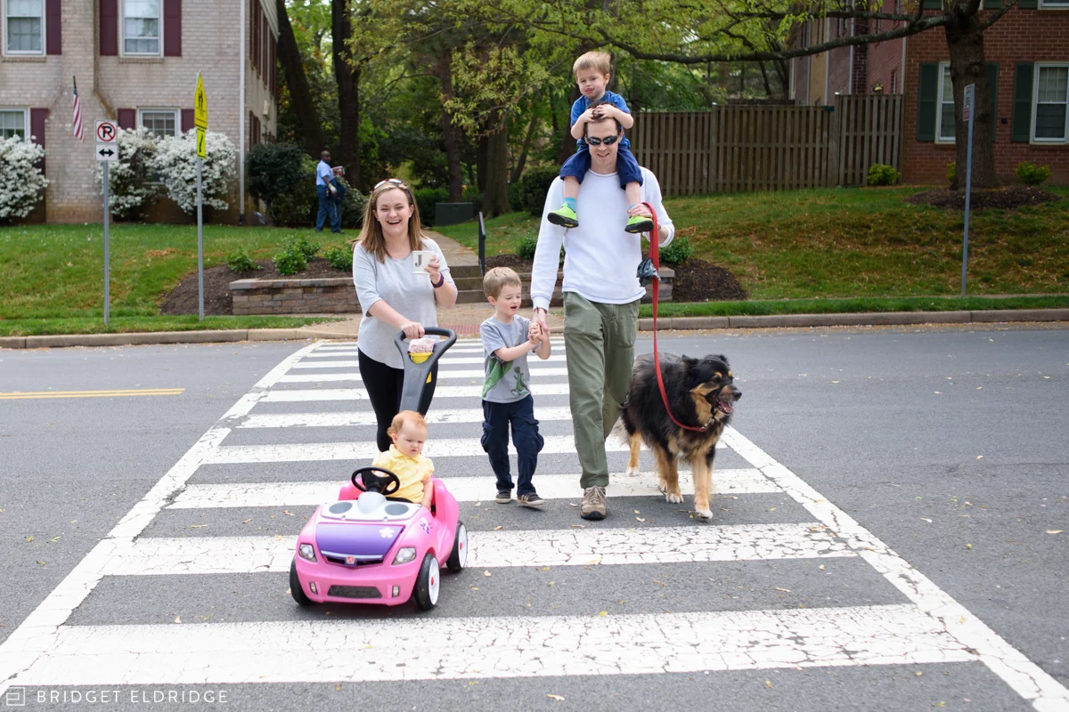 family crosses the street together on a neighborhood walk