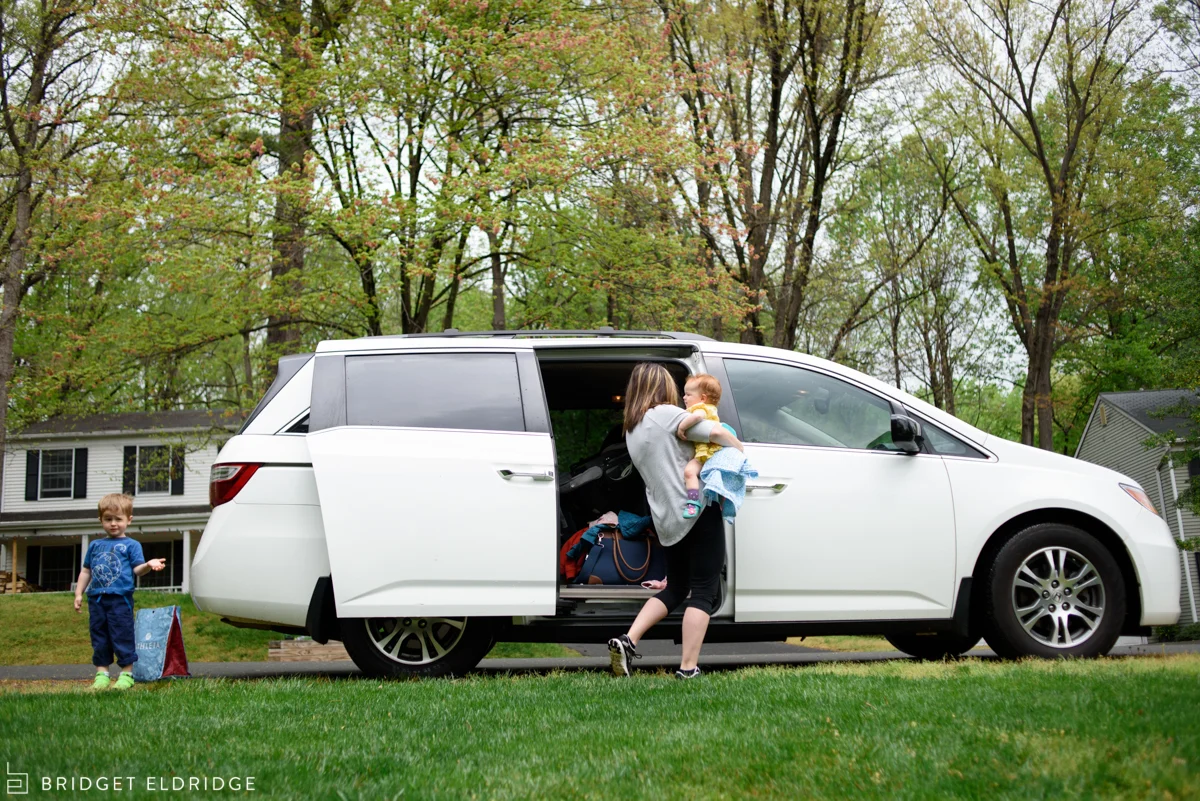 mom multitasks getting two kids out of the van