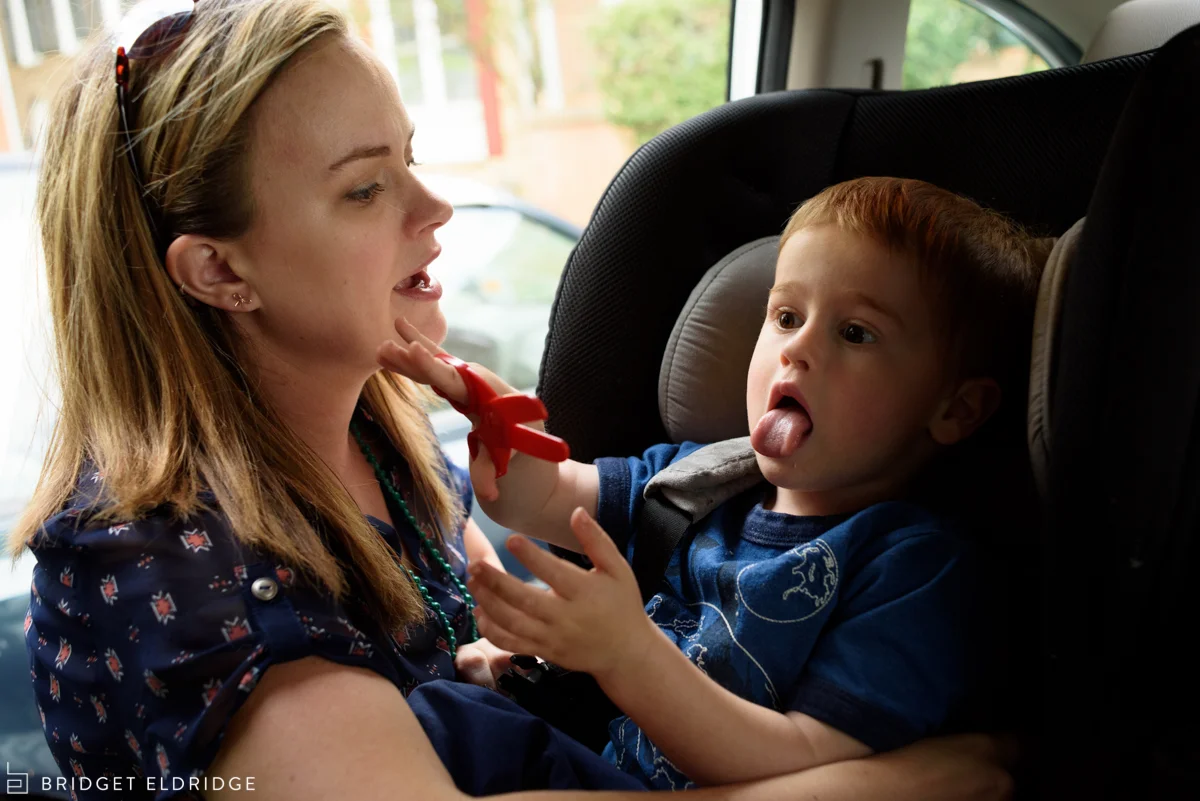 mom buckles son in the car