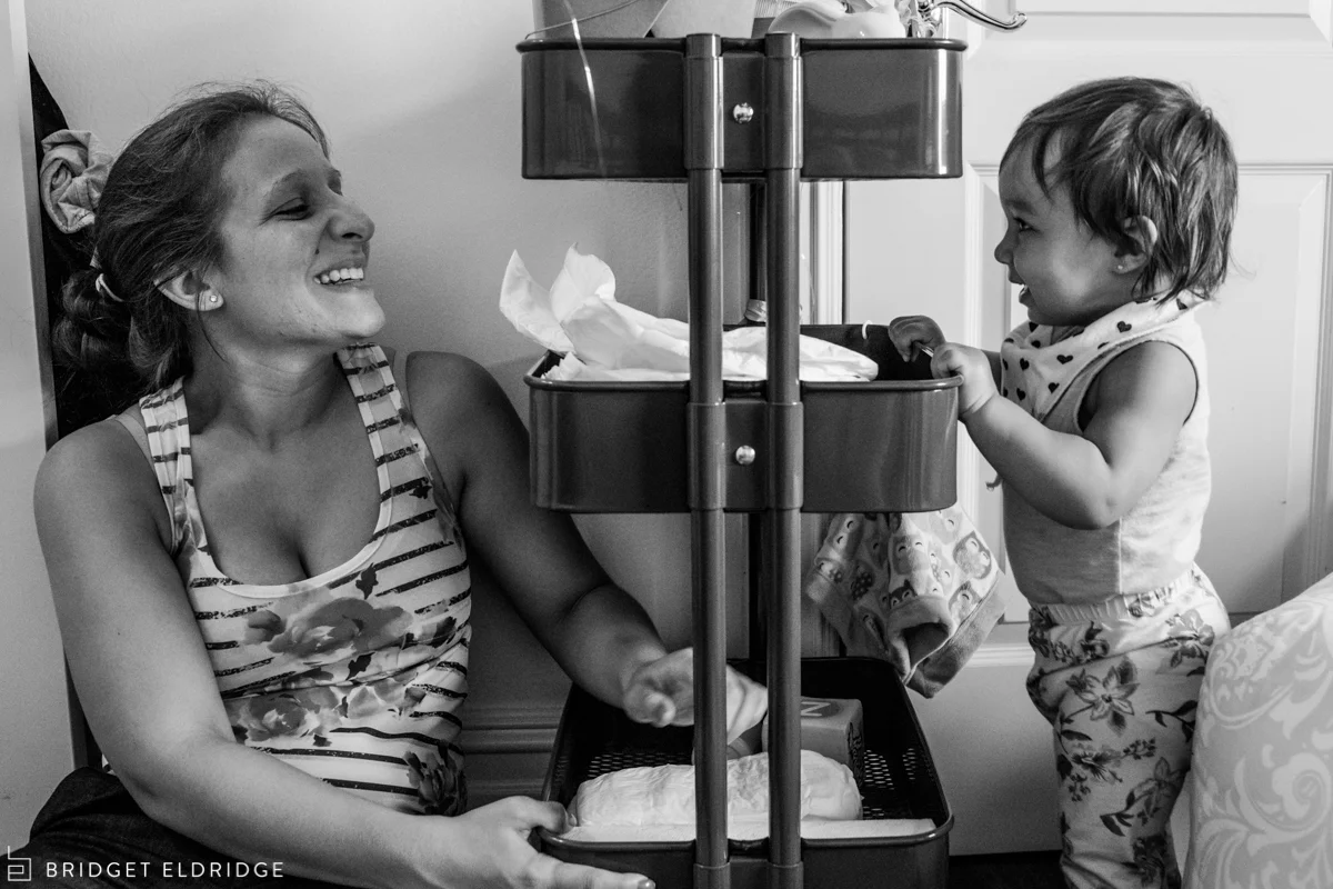 mom laughs as her daughter tries to pull over the diaper cart from ikea