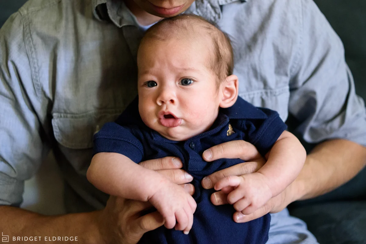 baby makes a funny face as dad holds him