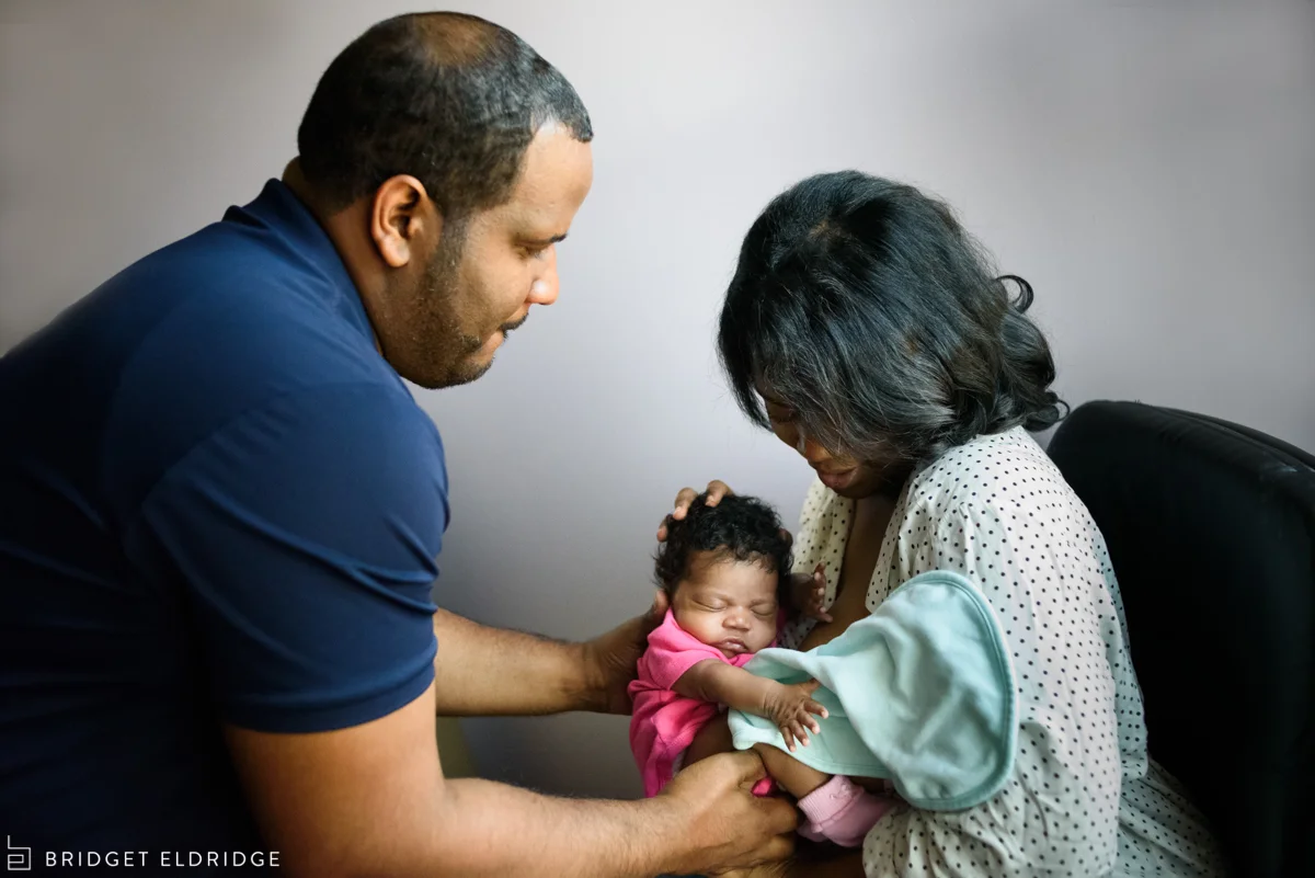 mom hands dad their newborn daughter after a feeding