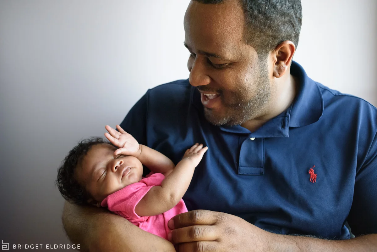 dad smiles at newborn daughter