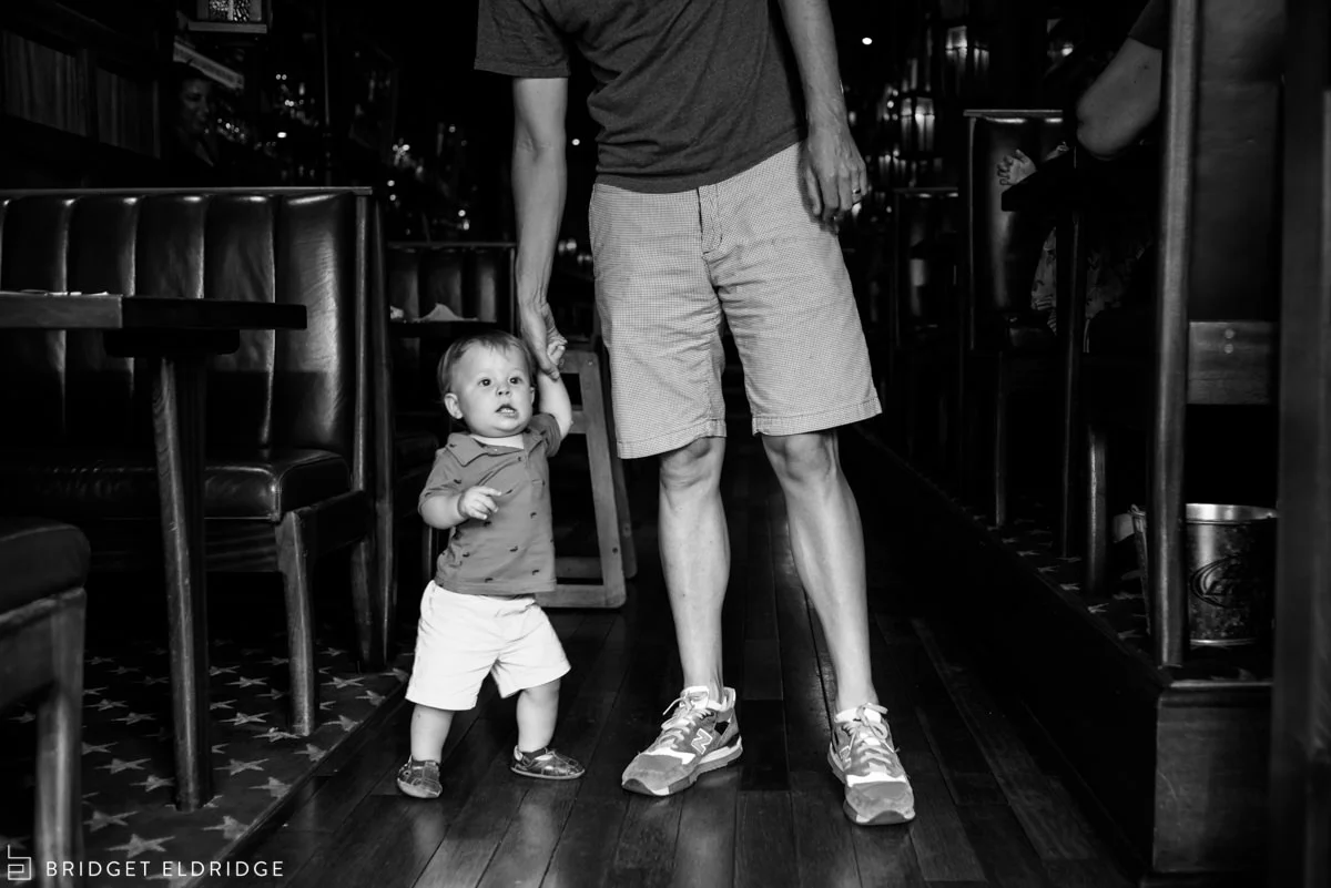 13 month old holds dad's hand as the family leaves Boxcar Tavens