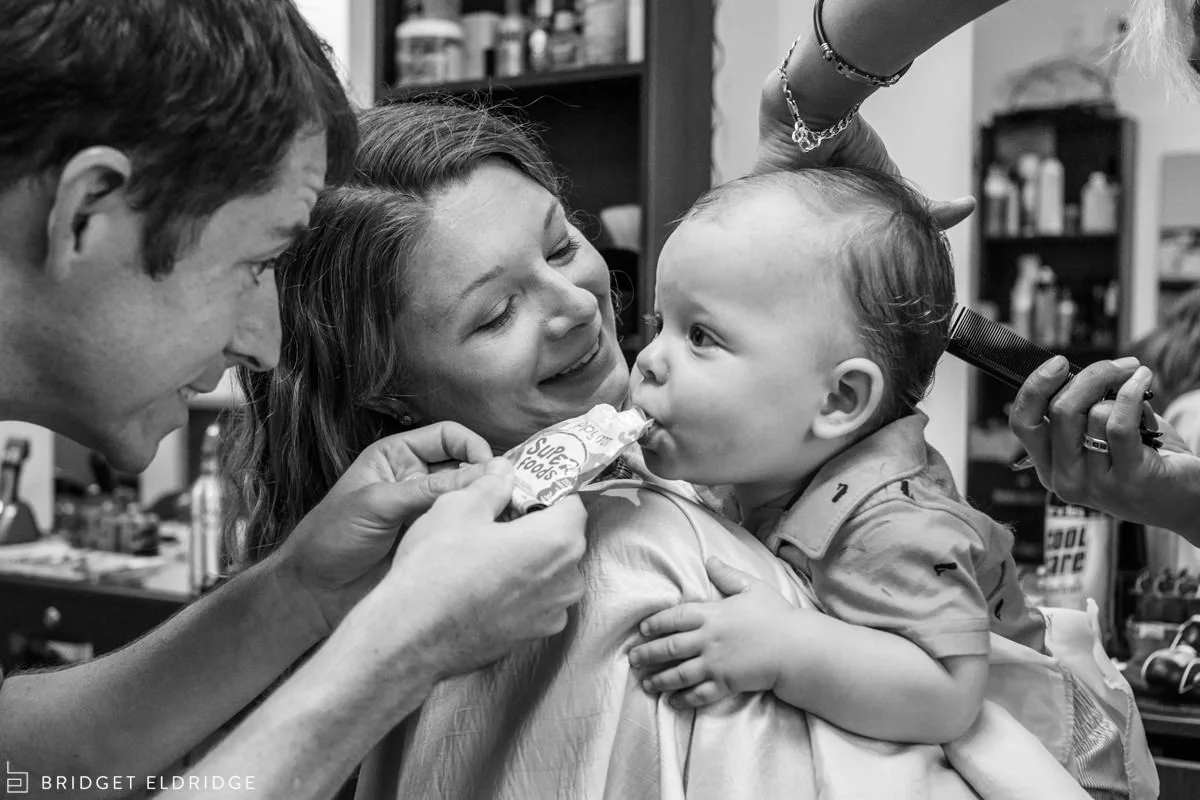 Dad gives toddler a pouch during his first haircut.
