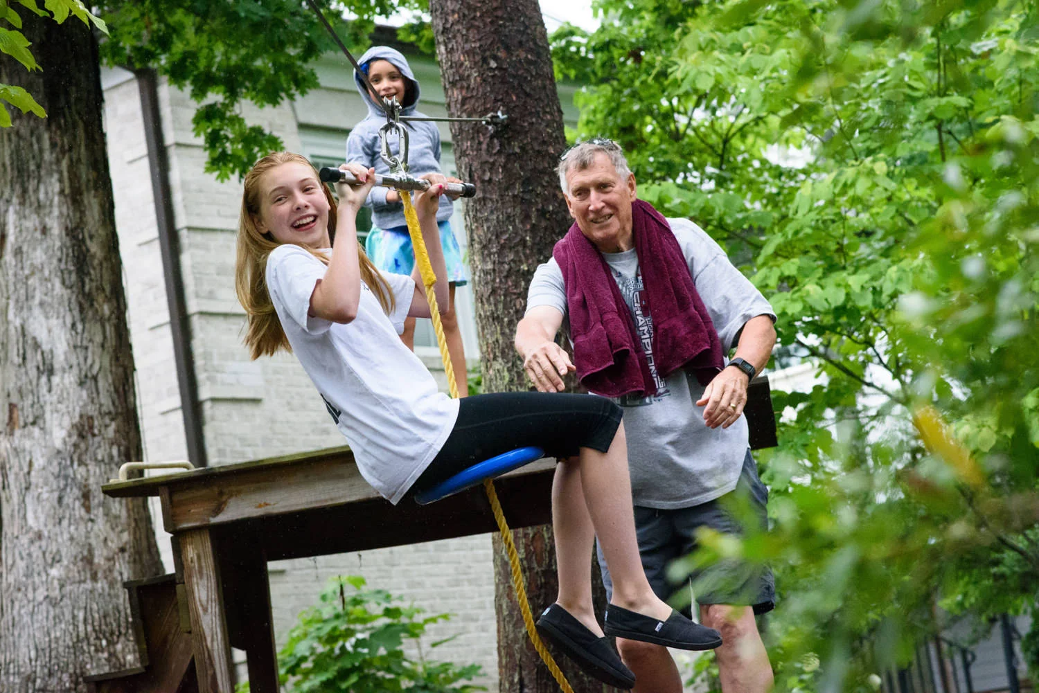 grandfather pushes his granddaughter on a zip line
