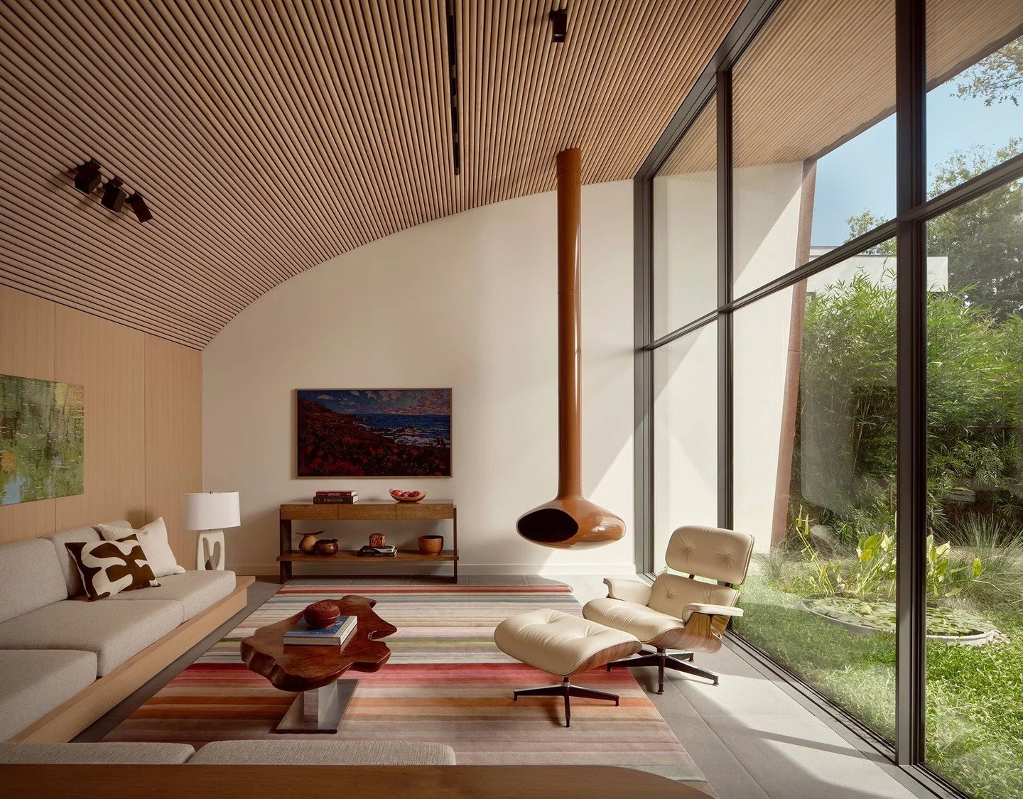 The interiors are defined by warm wood ceilings that continue from interior to exterior to form shaded patios. The ceilings themselves are made up of hundreds of half-round pine dowels whose curvatures echo the sloping roofs of the exterior while ori