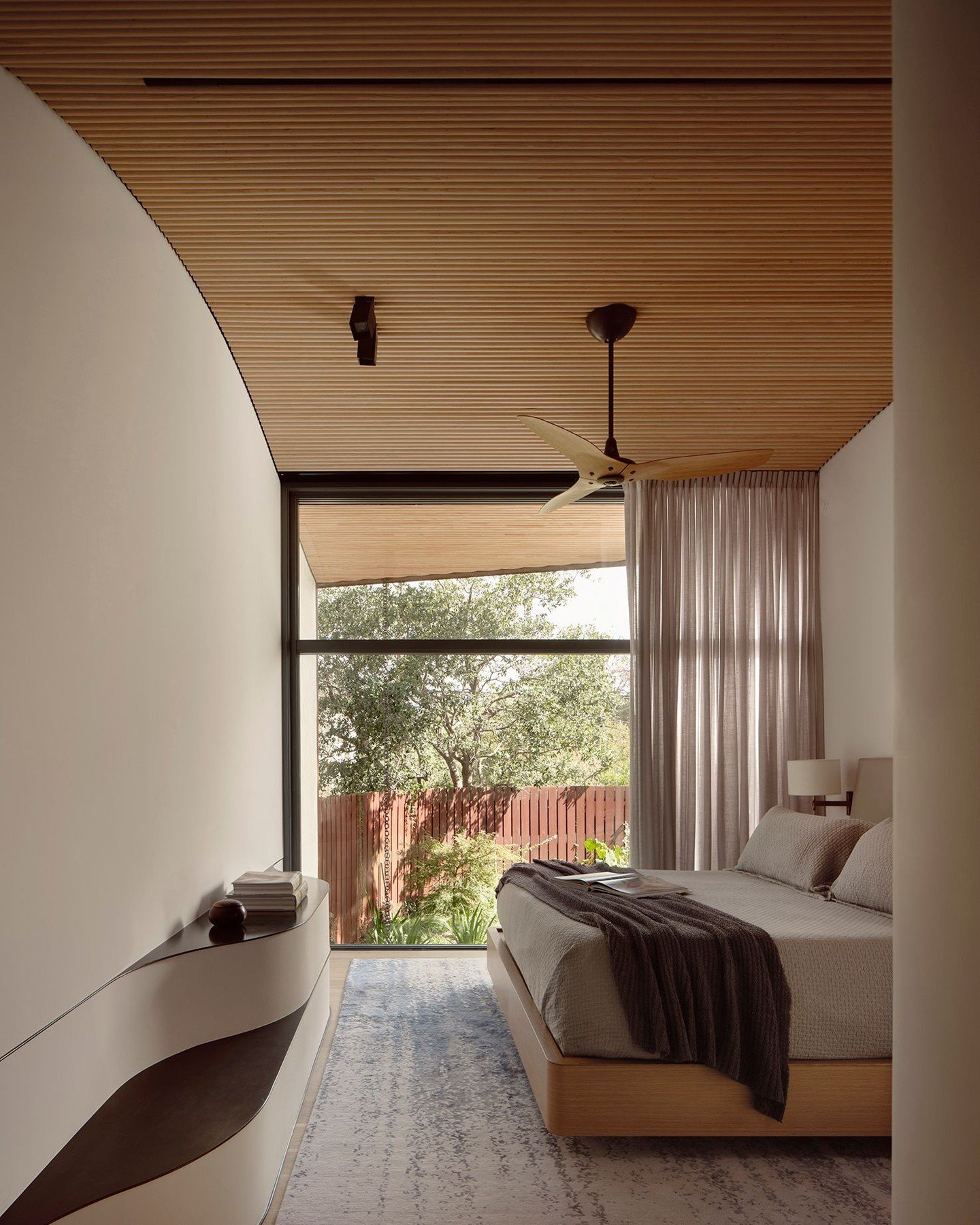 Facing the street, the primary bedroom takes advantage of its northern exposure with a wall of floor-to-ceiling steel-framed windows. A low weathering steel fence screens views from the street and sidewalk, and forms a secluded garden. #Residence1401