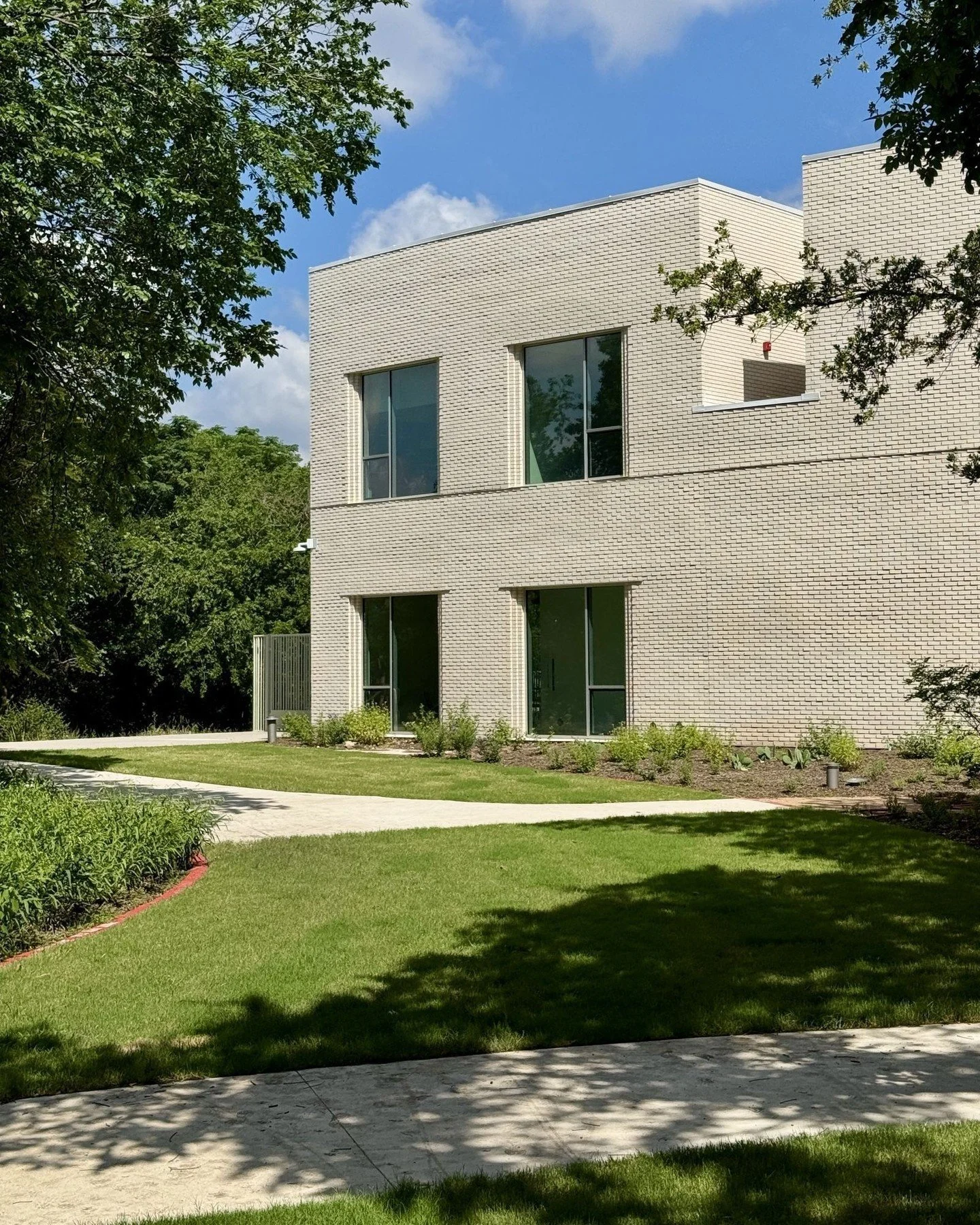 The new additions are clad in white brick with an offset pattern that, like the hand-chiseled precast concrete panels of the original structure, reflects a handmade quality. Large windows bring natural light into all of the occupied spaces, with oper